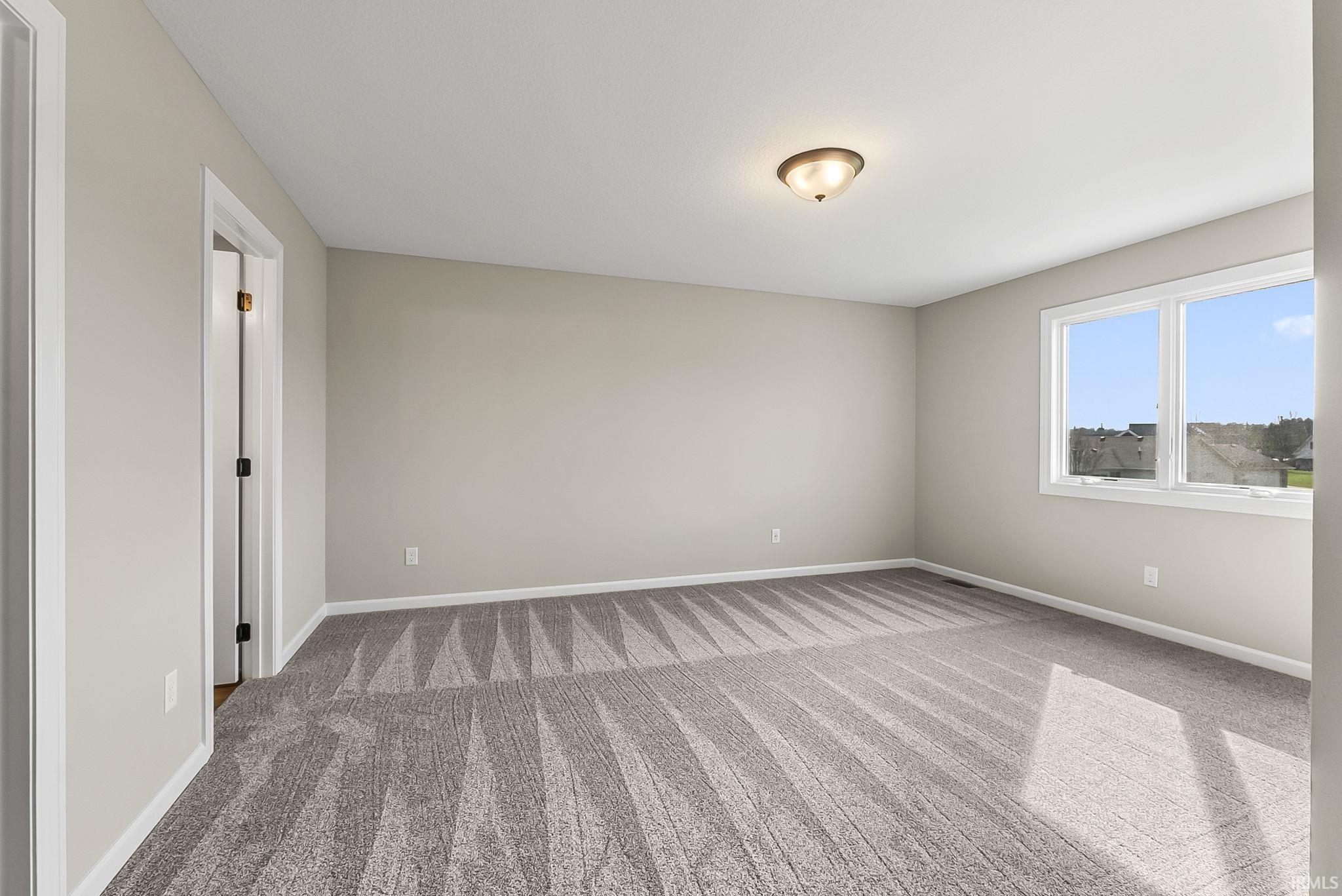 Empty room featuring light colored carpet and baseboards