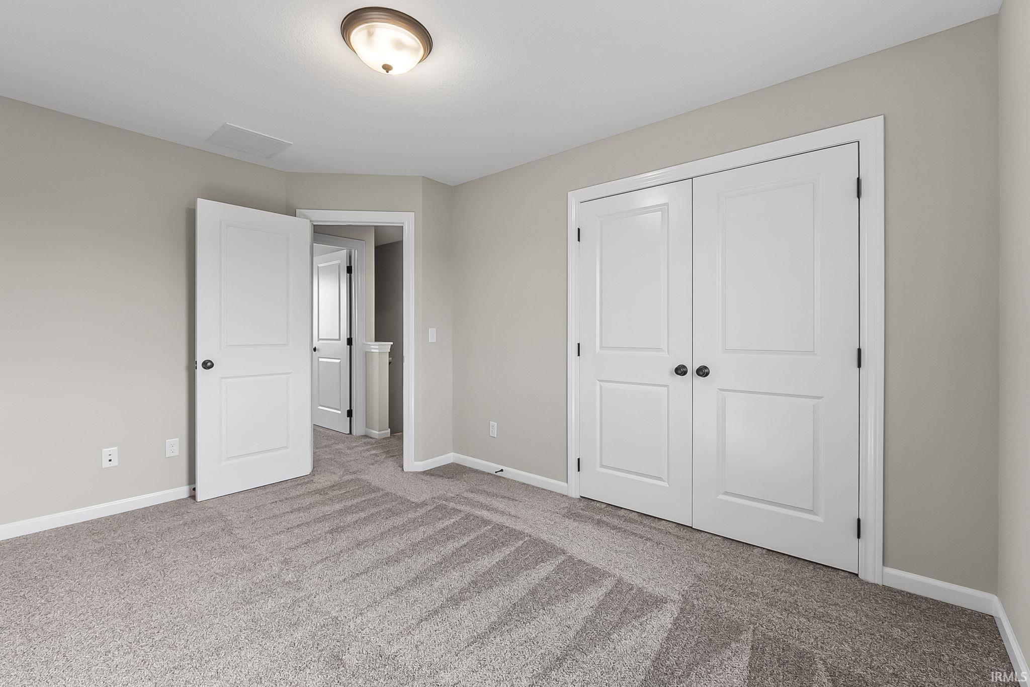 Unfurnished bedroom with light carpet and a closet