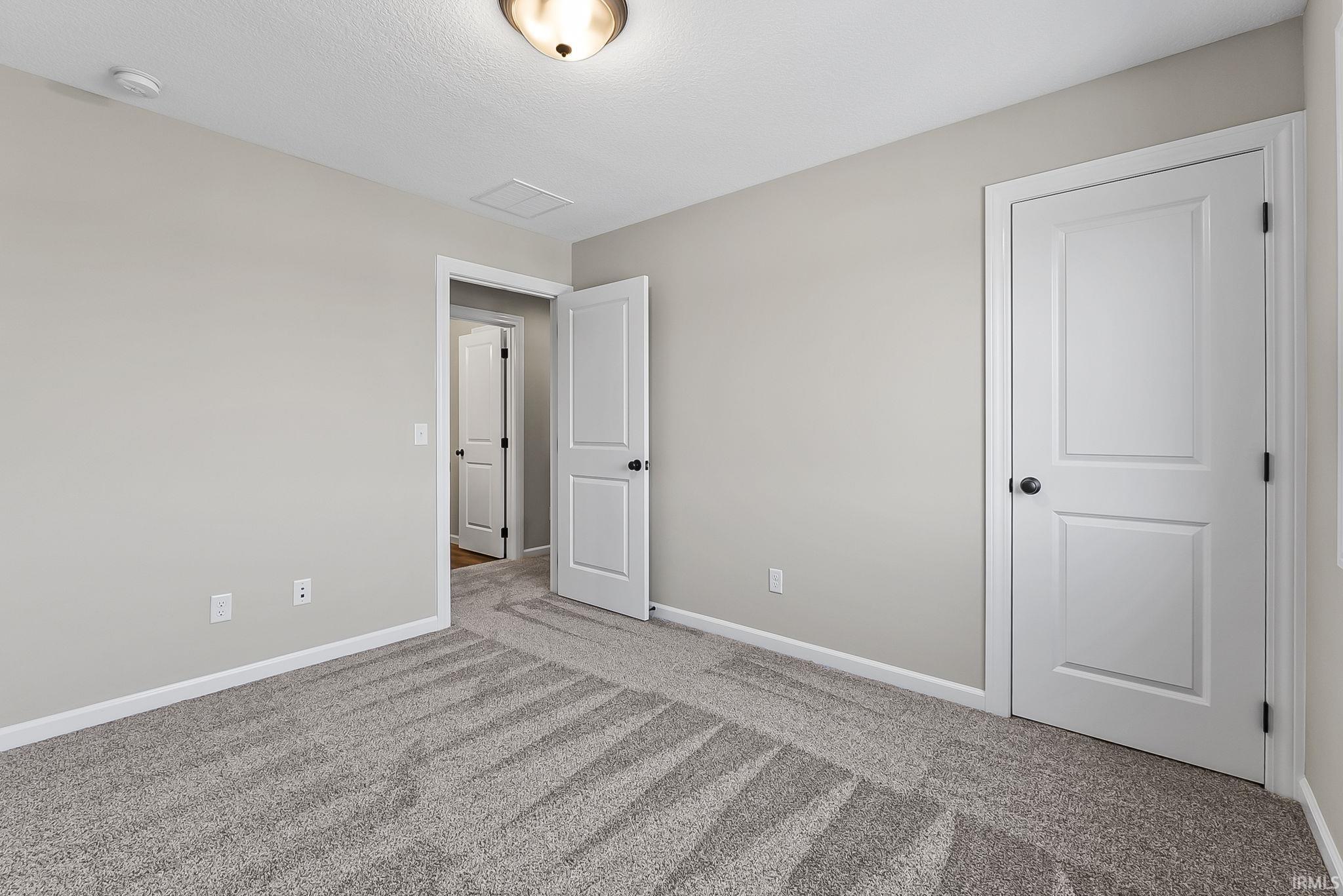 Unfurnished bedroom featuring light carpet and baseboards