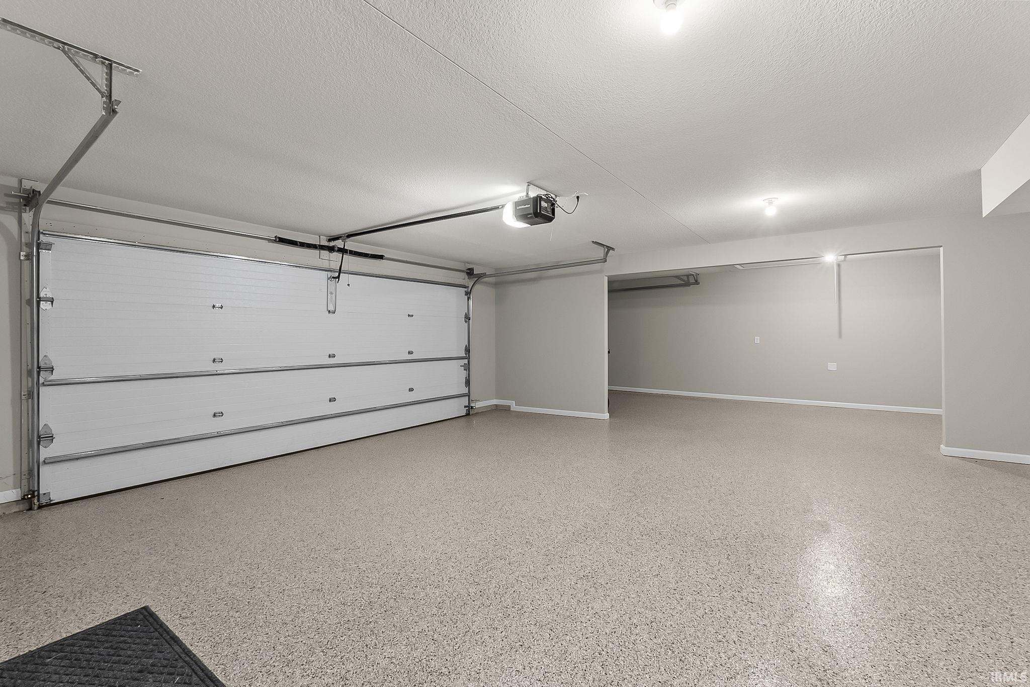 Garage featuring baseboards and a garage door opener