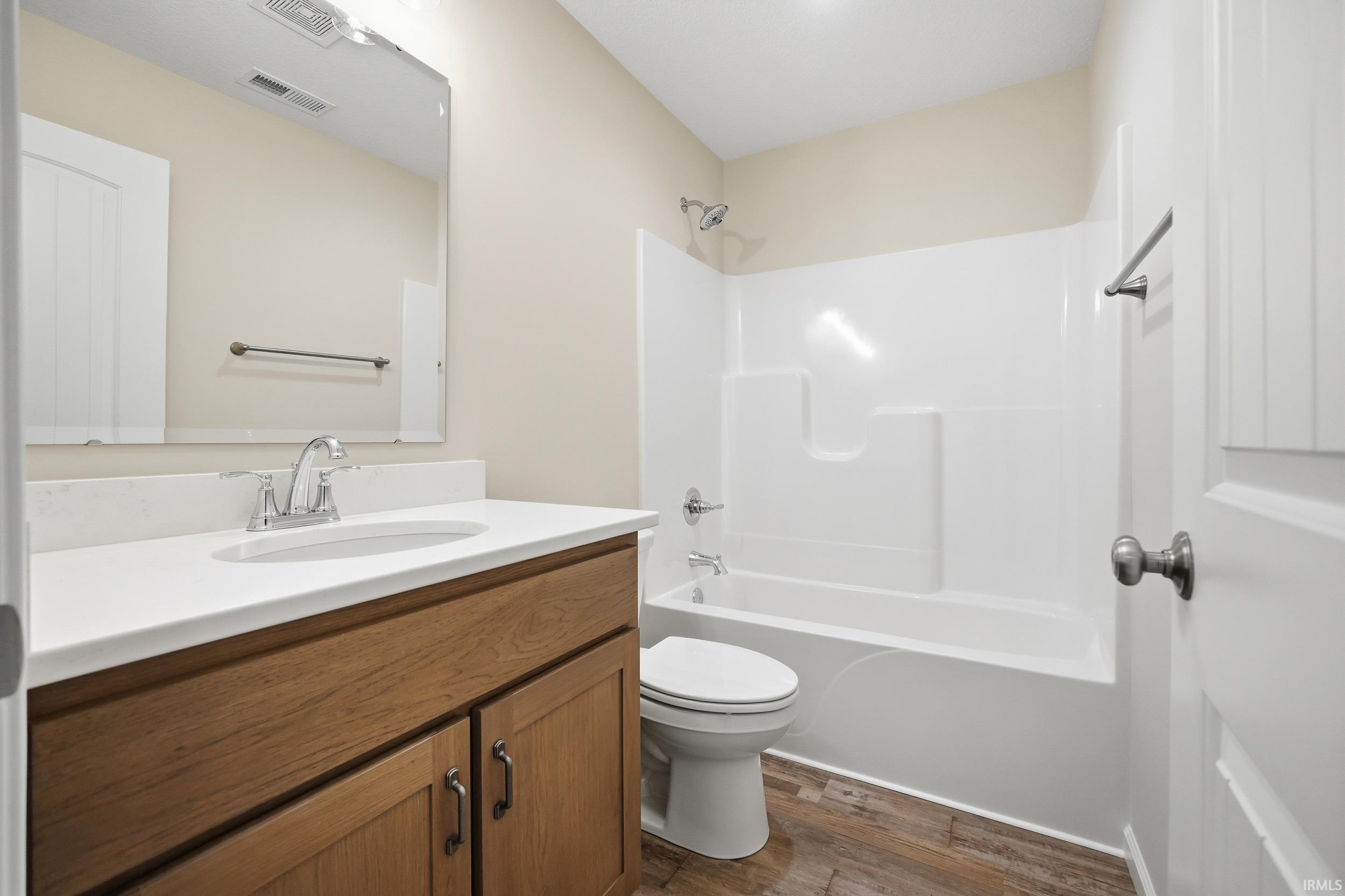 Full bath featuring vanity, bathing tub / shower combination, and dark wood-style flooring