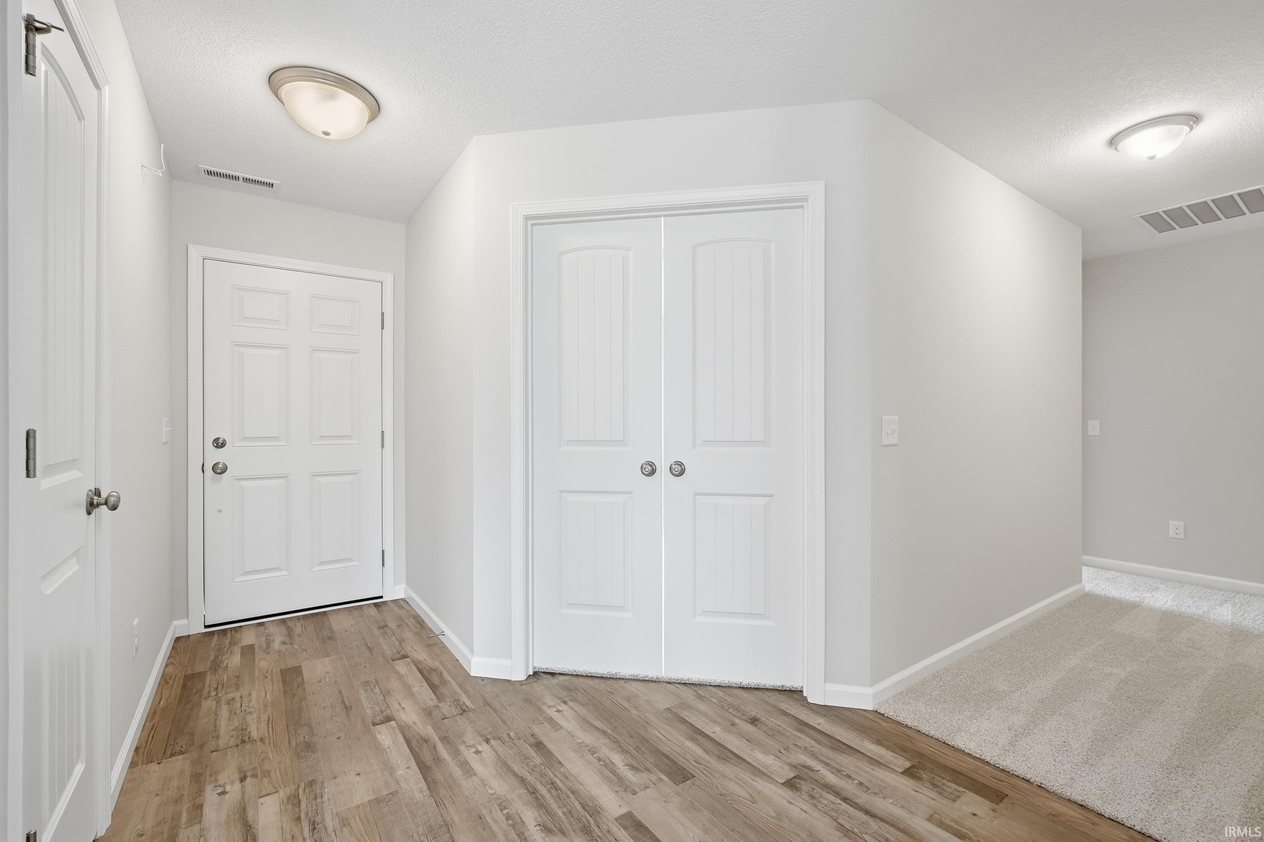 Foyer featuring light wood-style flooring and a textured ceiling