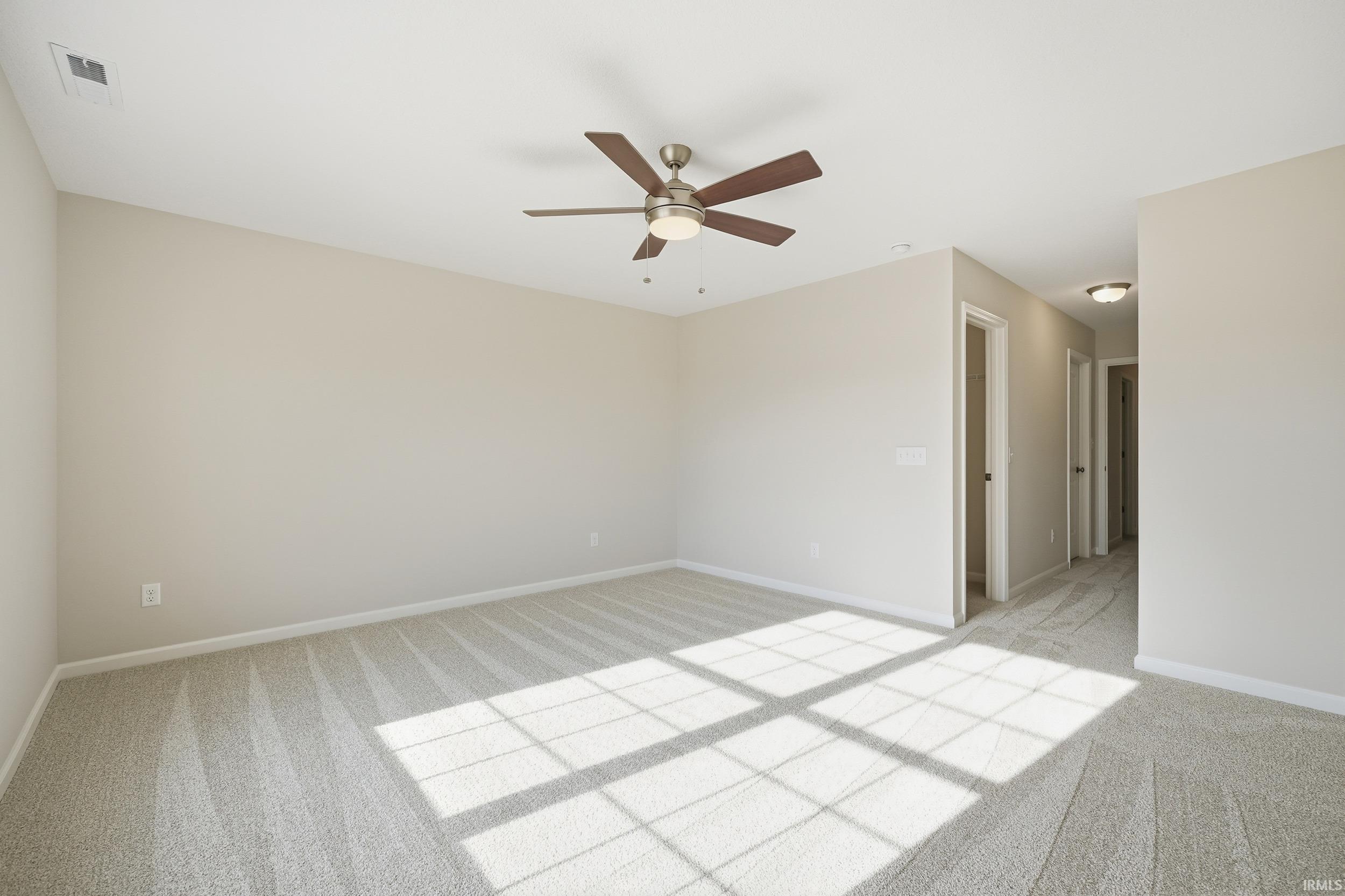 Empty room with light carpet and a ceiling fan