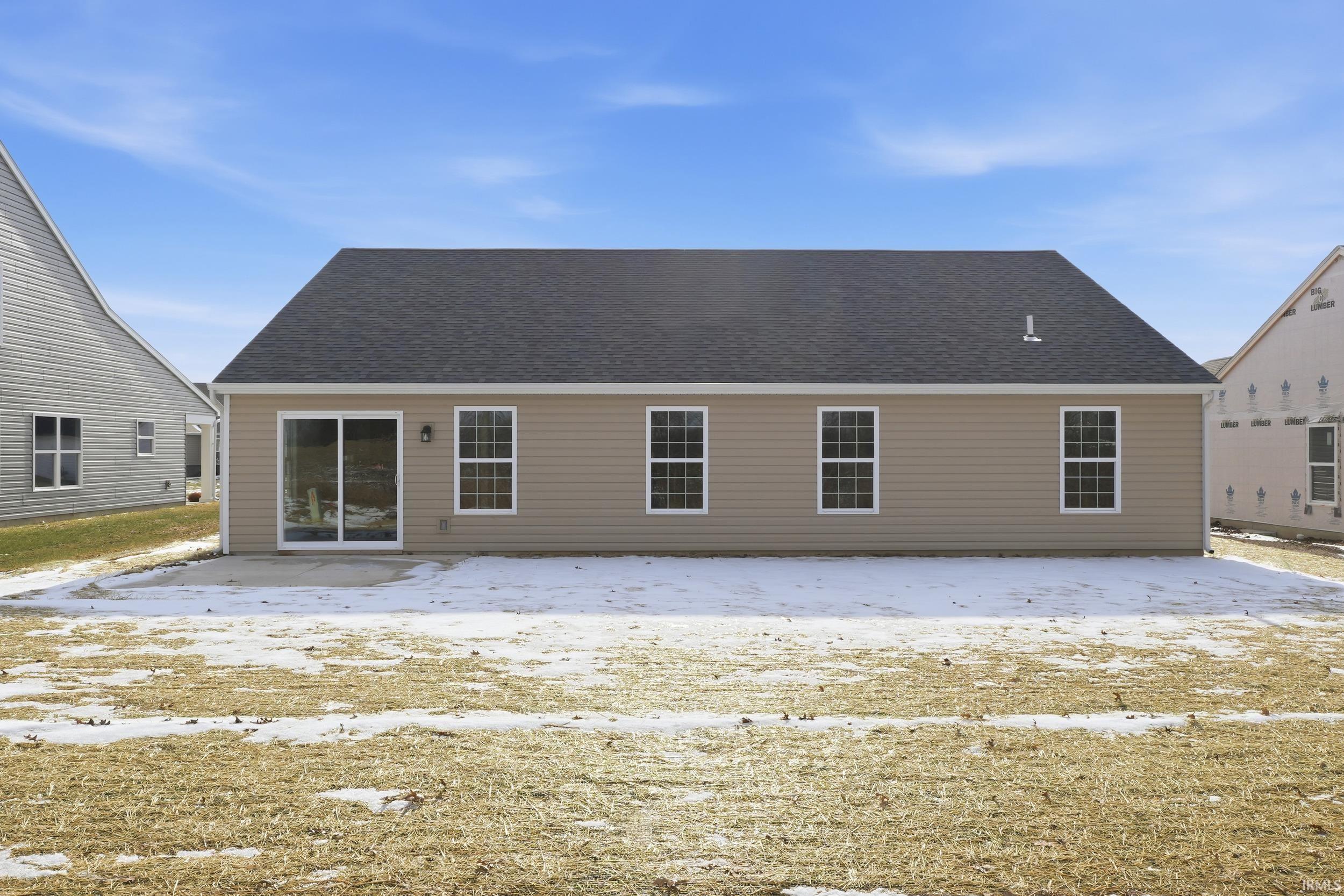 Snow covered rear of property with roof with shingles and a patio