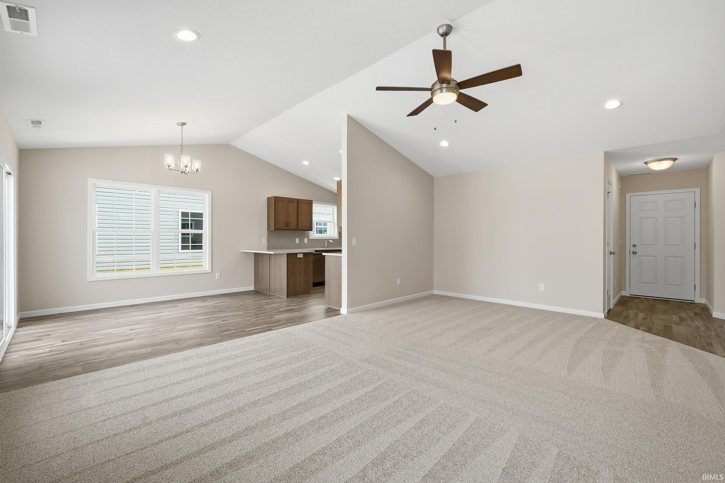 Unfurnished living room with recessed lighting, a chandelier, lofted ceiling, and ceiling fan