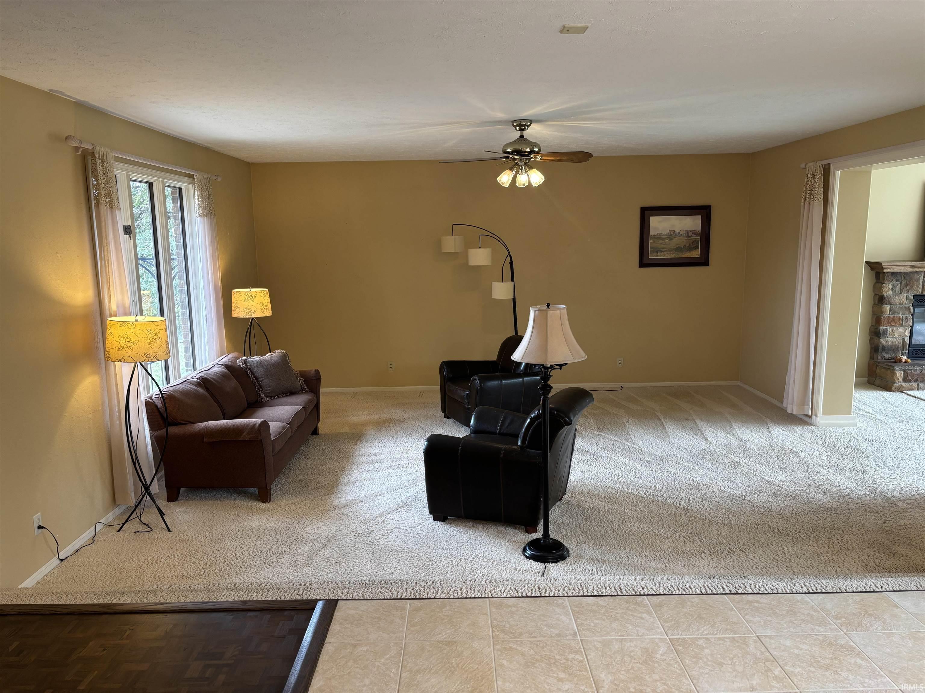Living room with light carpet, ceiling fan, and a fireplace