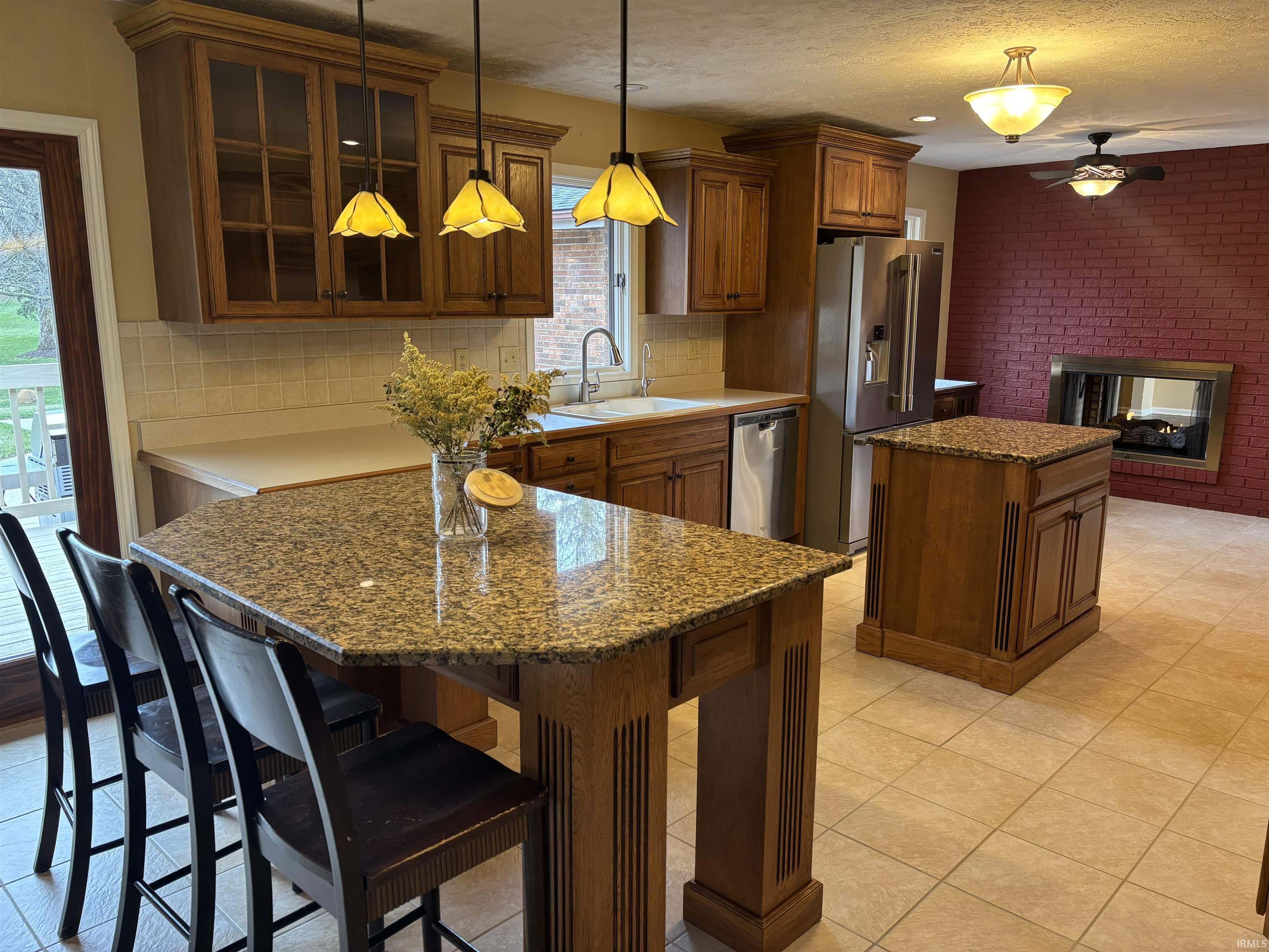 Kitchen featuring a kitchen island, ceiling fan, stainless steel appliances, decorative backsplash, and dark stone countertops