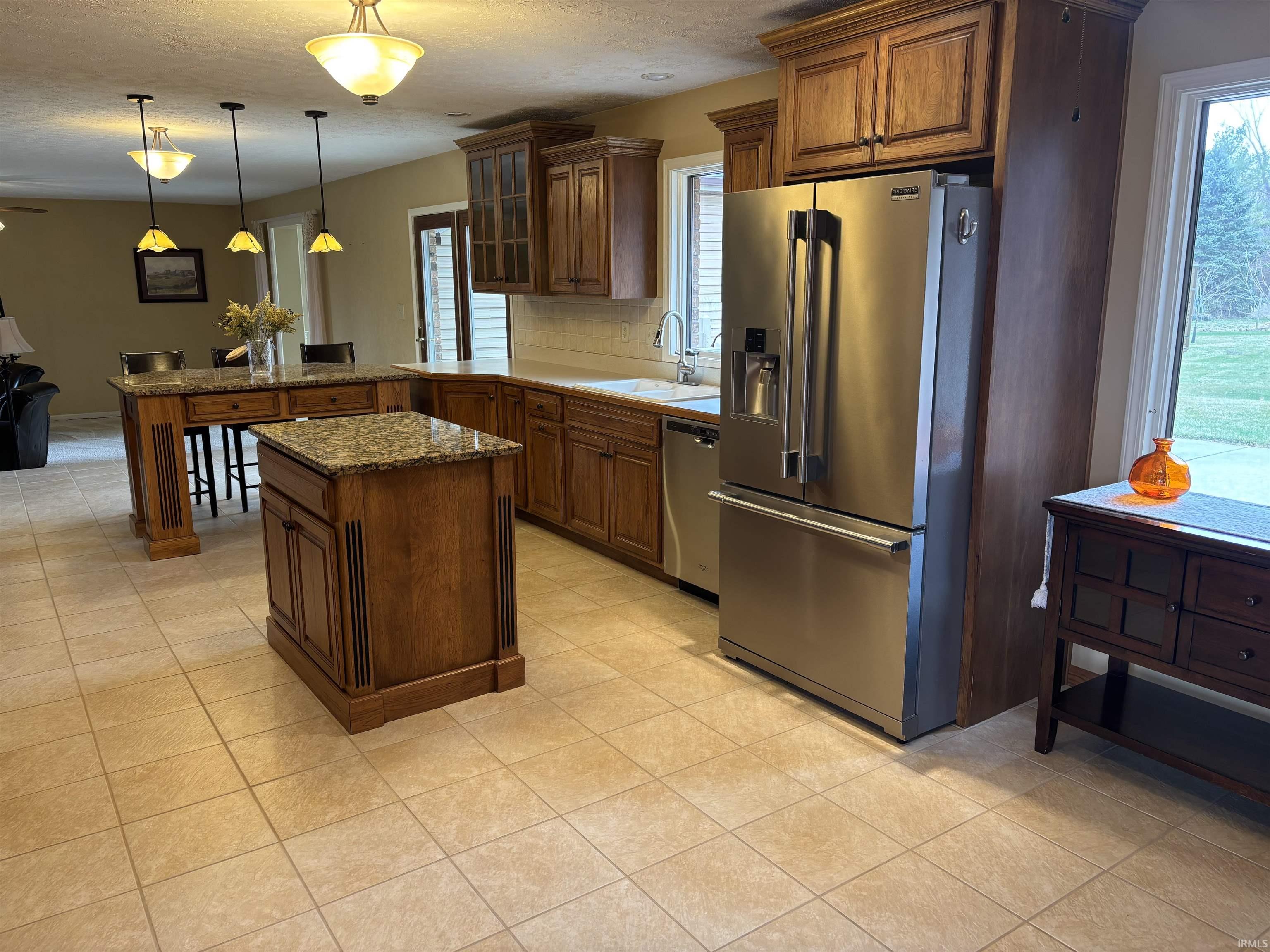 Kitchen featuring glass insert cabinets, stainless steel appliances, a peninsula, wood finish cabinetry, and hanging light fixtures