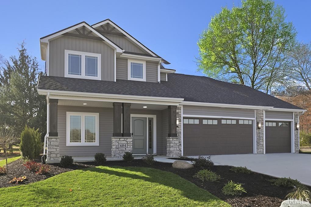 Craftsman house with stone siding, covered porch, board and batten siding, a front yard, and a garage