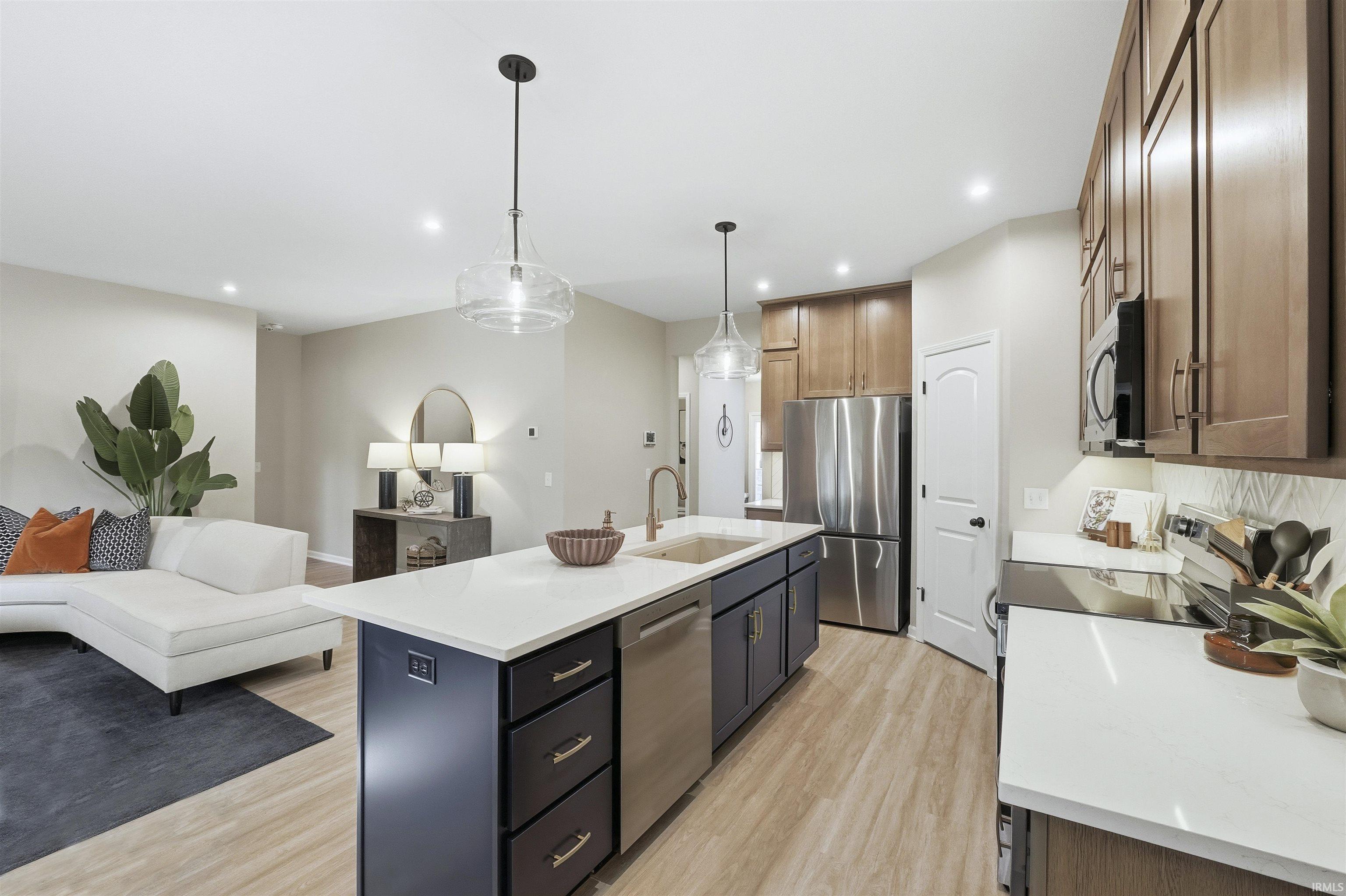 Kitchen with open floor plan, stainless steel appliances, light wood-type flooring, pendant lighting, and recessed lighting