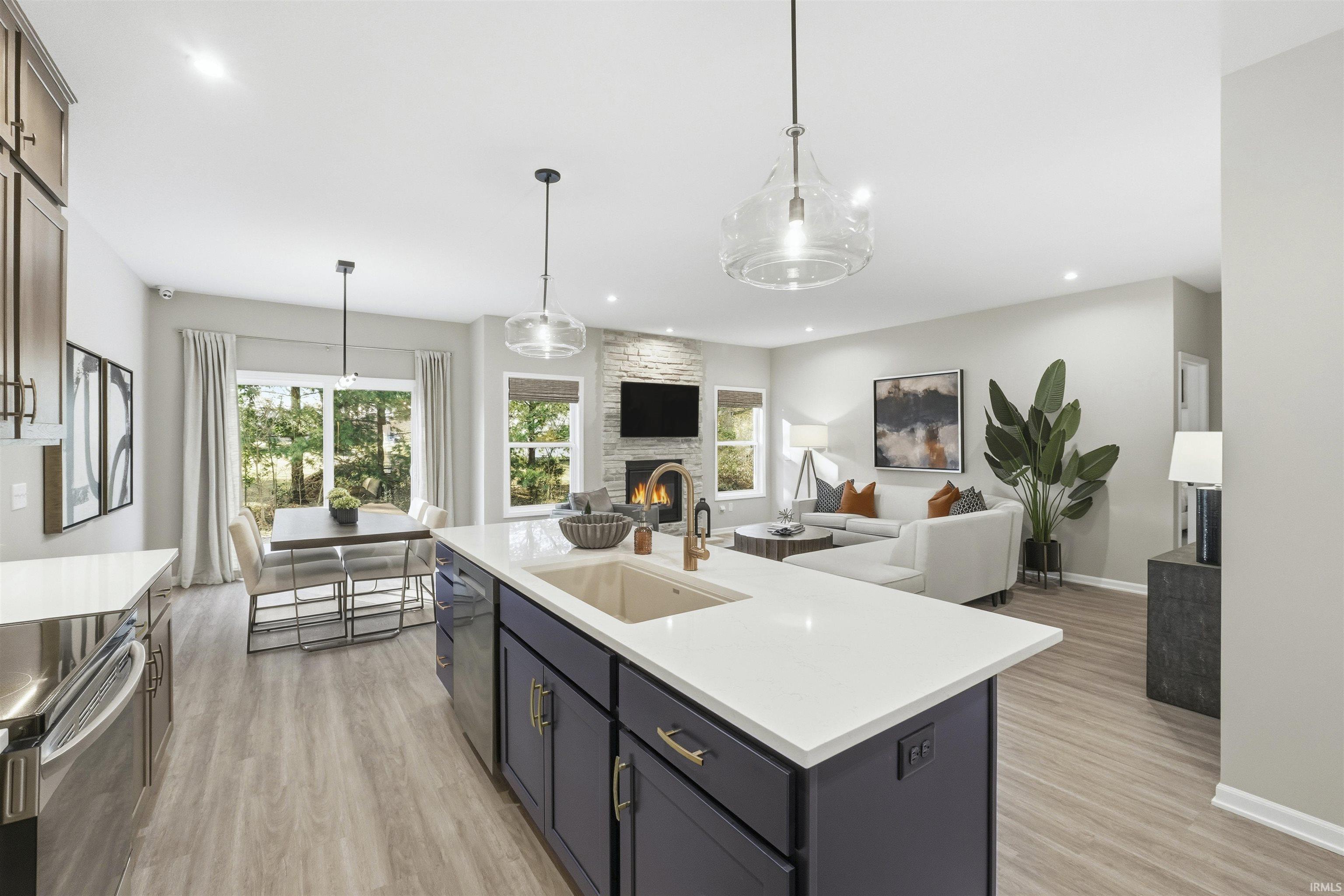 Kitchen featuring open floor plan, hanging light fixtures, a fireplace, light wood finished floors, and recessed lighting