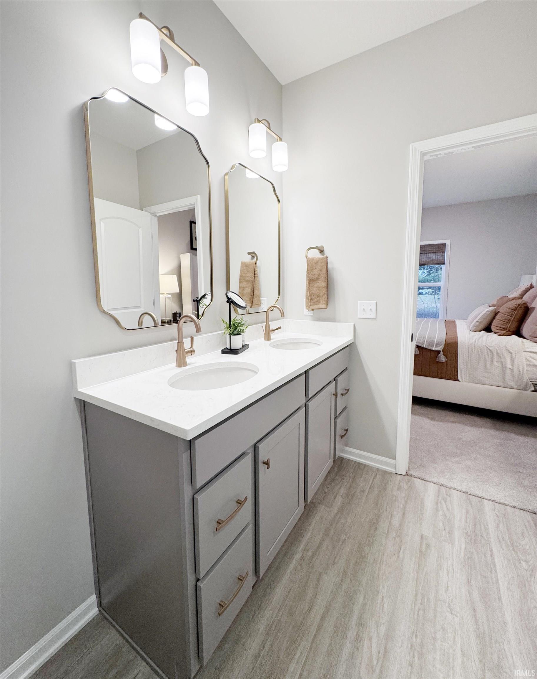 Owner Suite Bathroom with double vanity and light wood finished floors