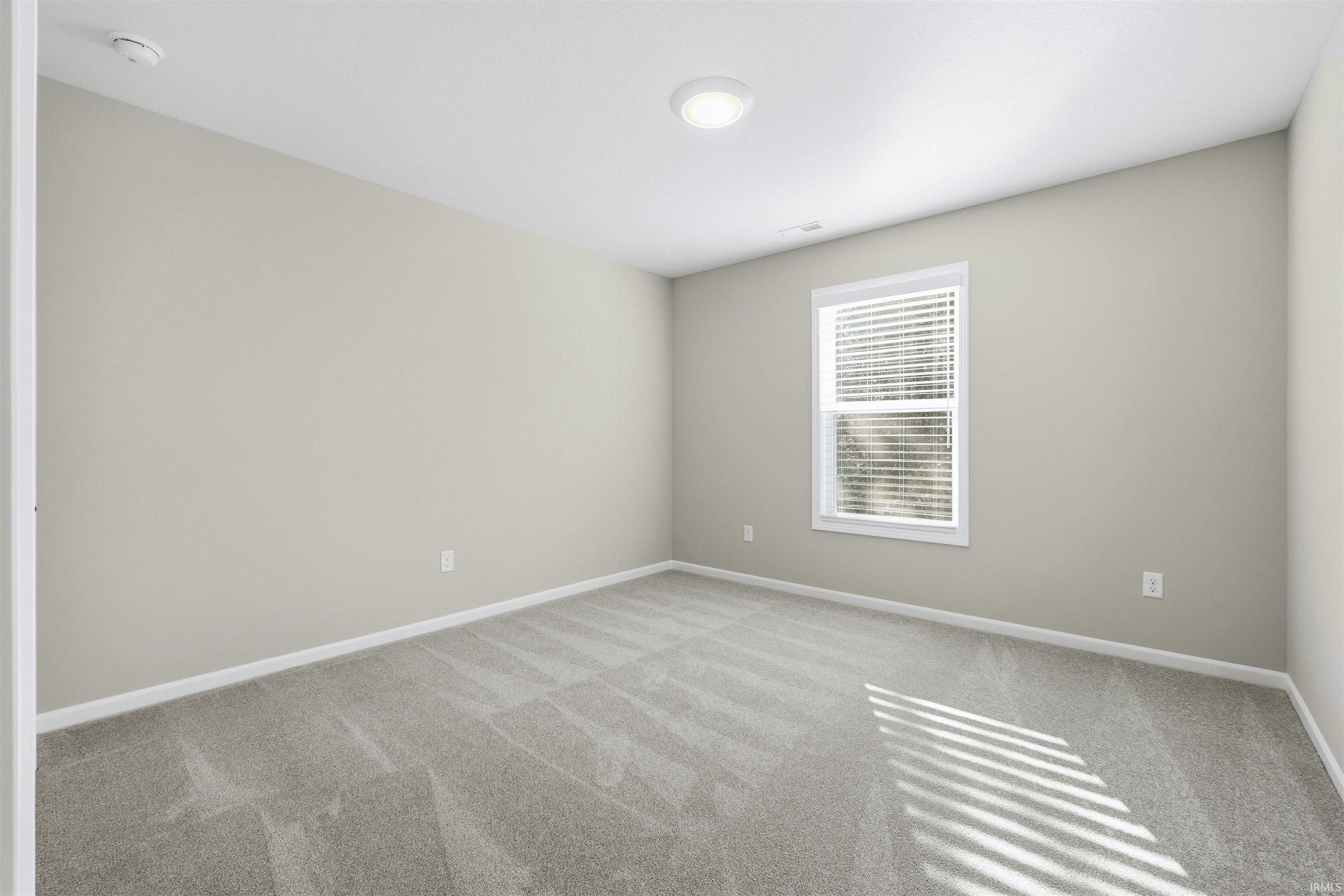 Carpeted spare room featuring baseboards