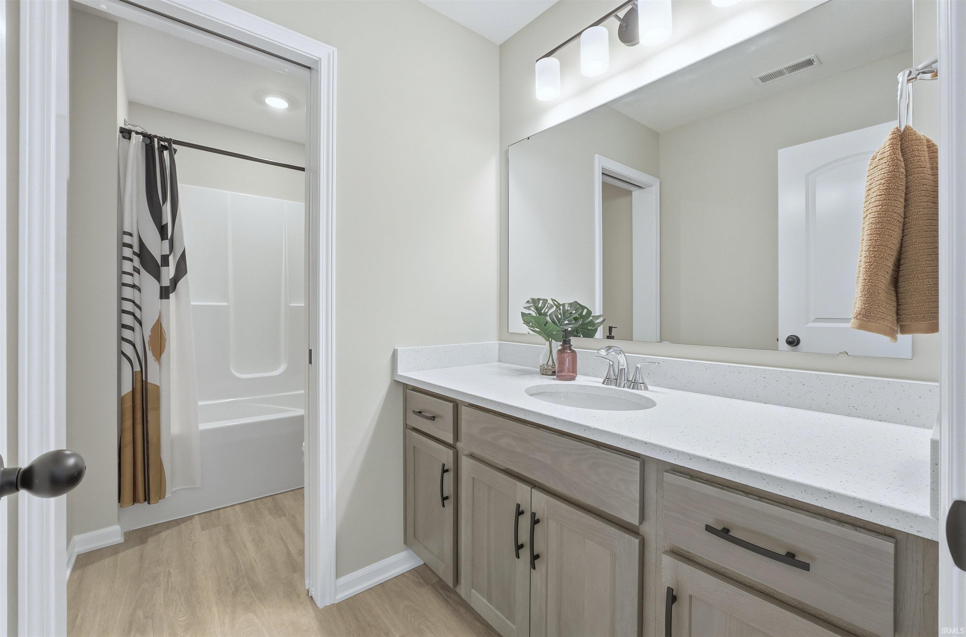Bathroom featuring vanity, shower / bath combination with curtain, and light wood-type flooring