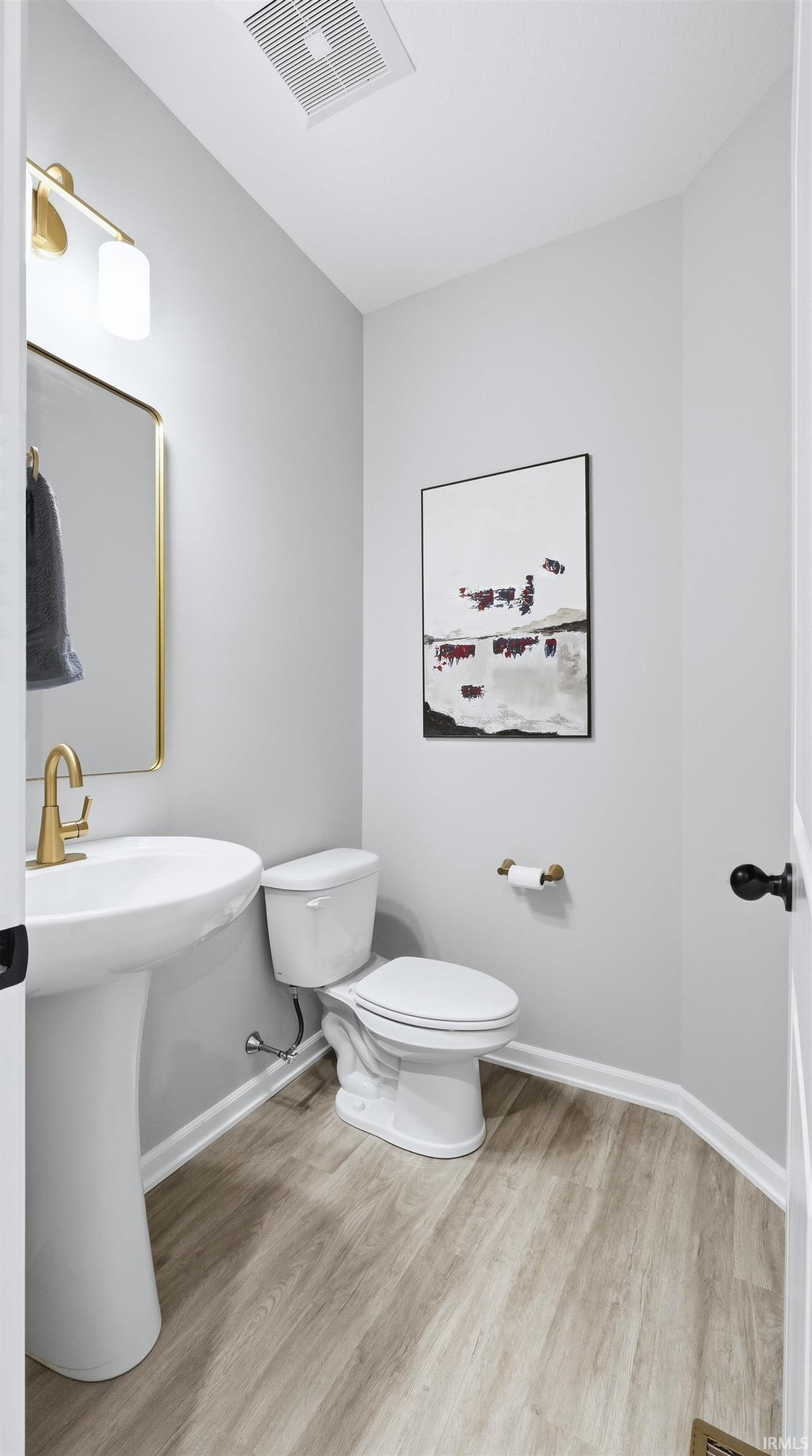 Half bathroom with toilet and light wood-style floors
