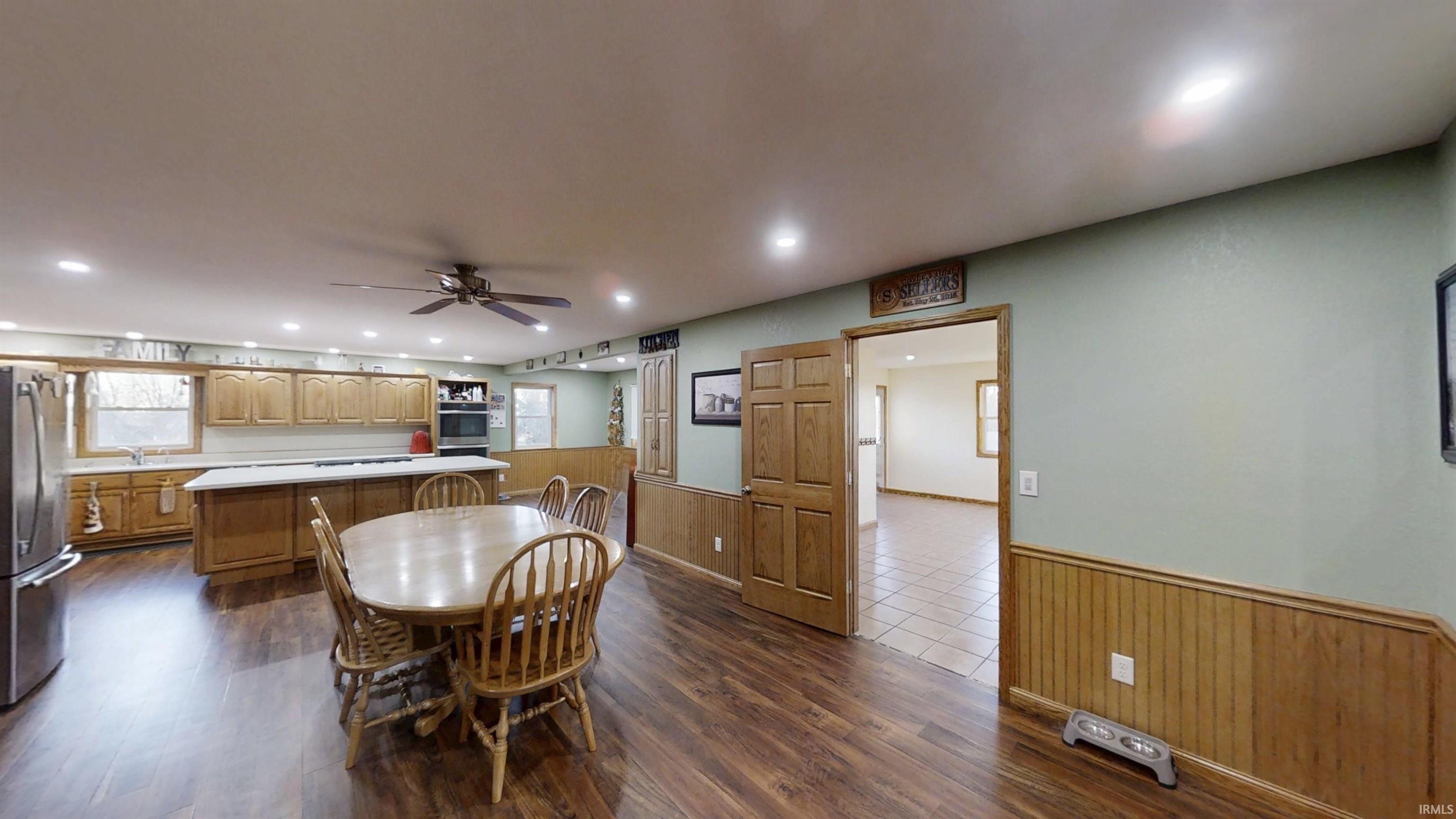 Dining area with wainscoting, wood-style flooring, recessed lighting, and a ceiling fan
