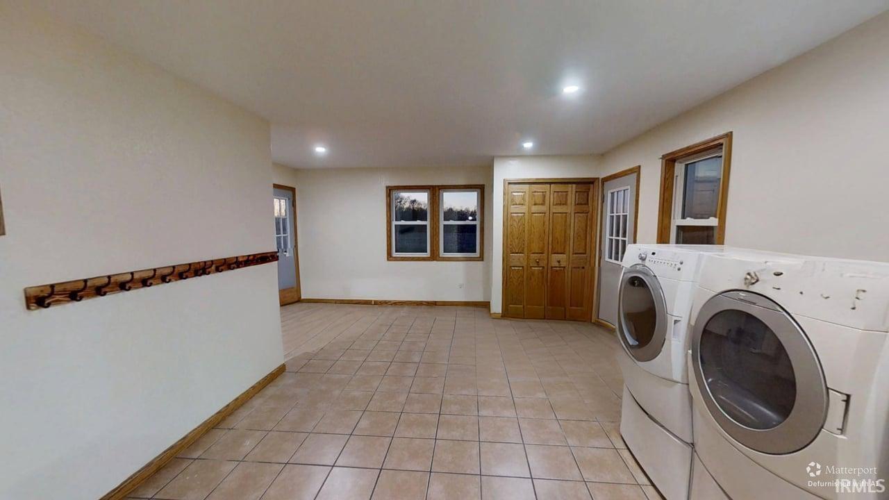Washroom with light tile patterned flooring, recessed lighting, and washer and dryer