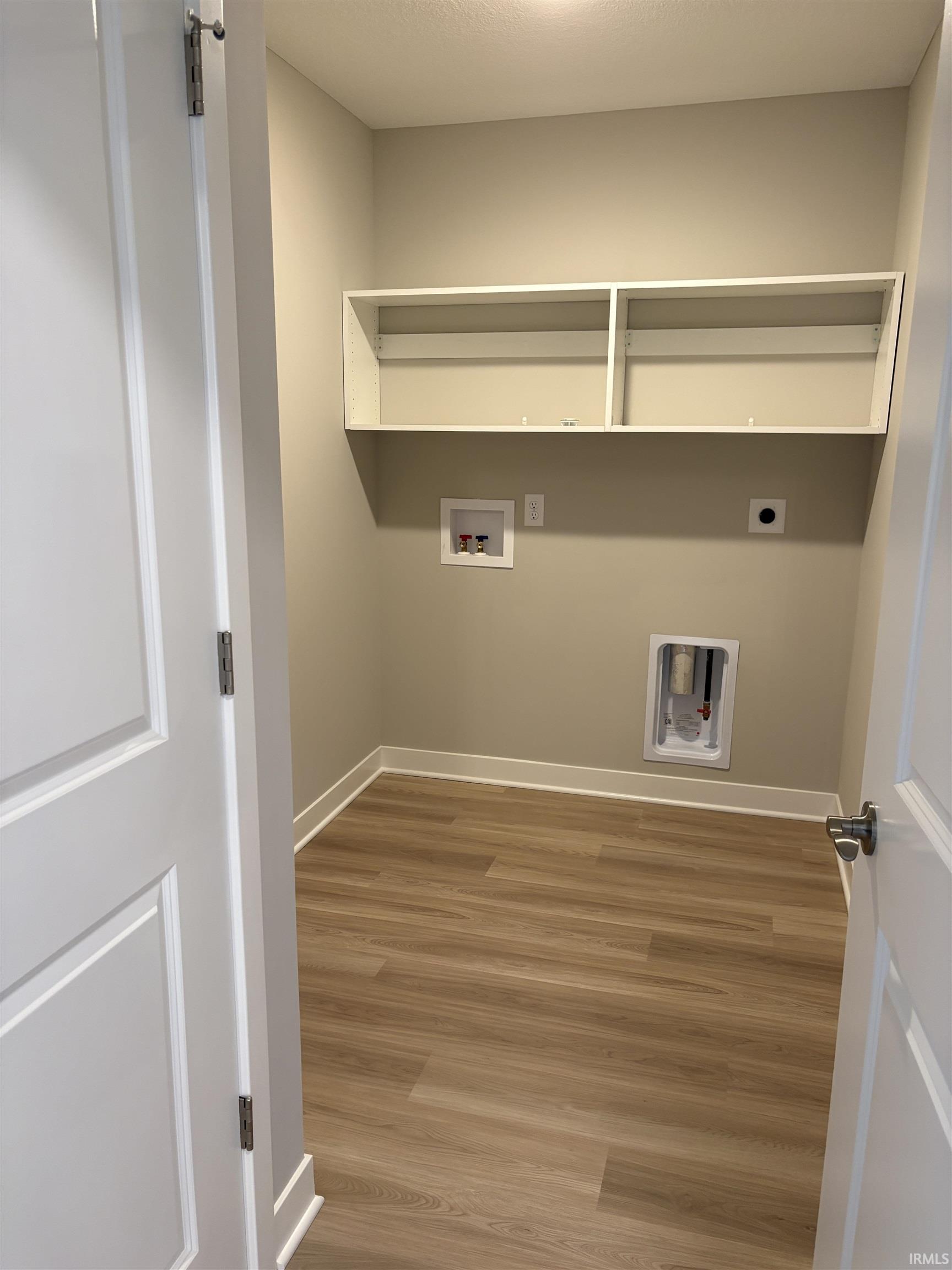 Laundry room featuring wood-finish flooring, light neutral wall paint, and white trim