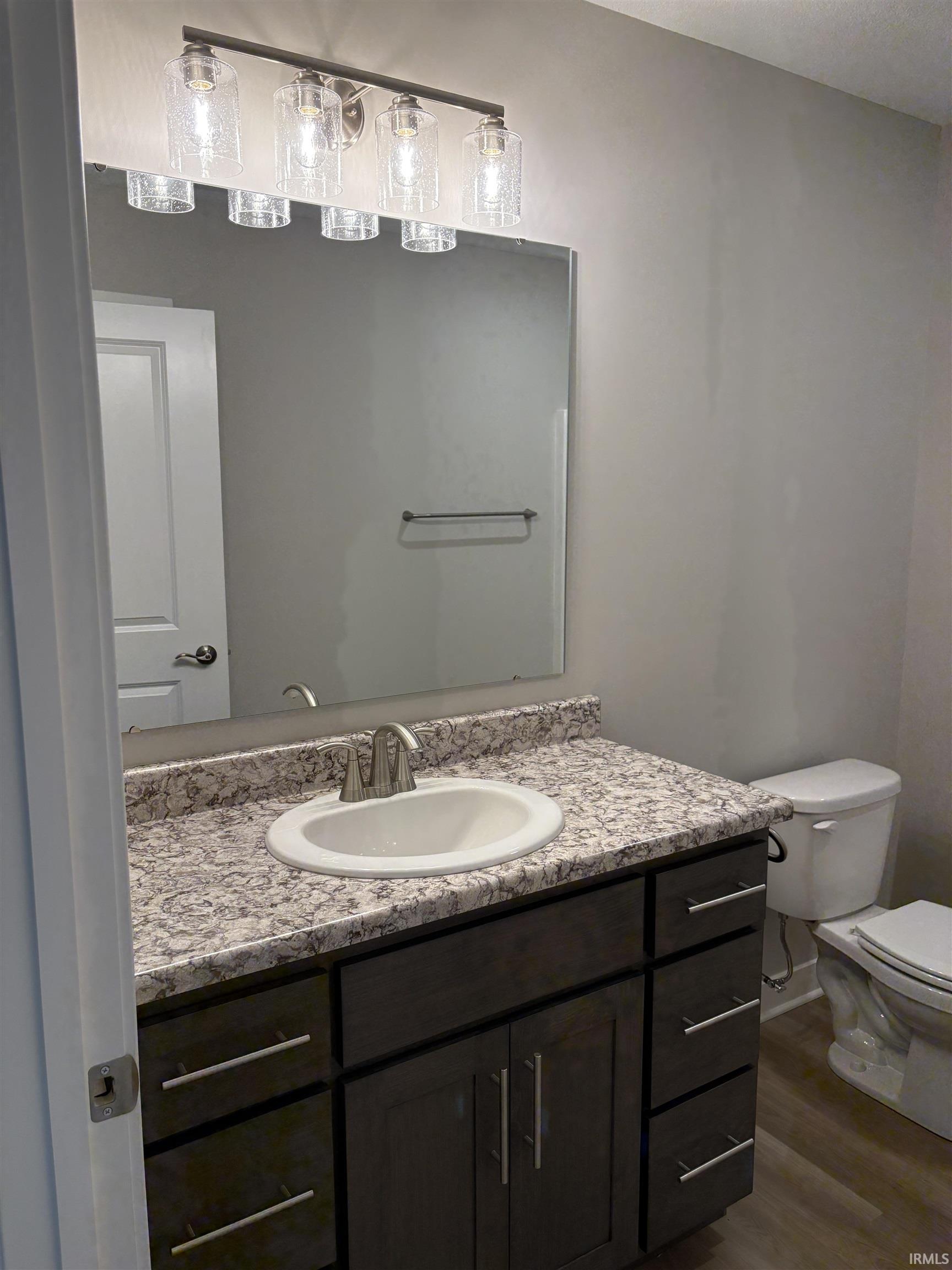 Bathroom featuring a dark wood-finish vanity with ample storage, a white oval undermount sink, and a speckled countertop