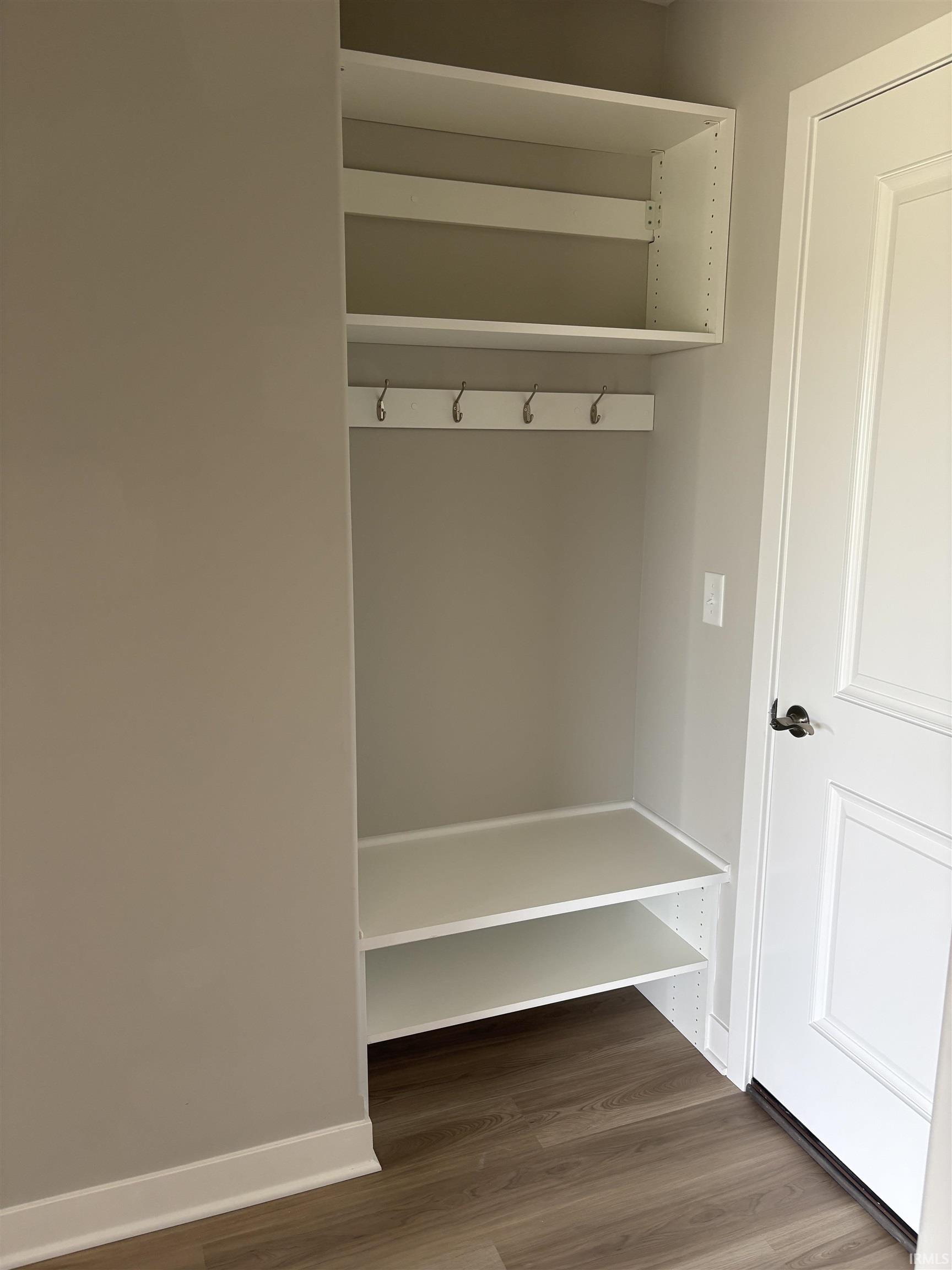 Built-in entryway organization featuring upper shelving, a coat rack with five hooks, and lower shoe storage