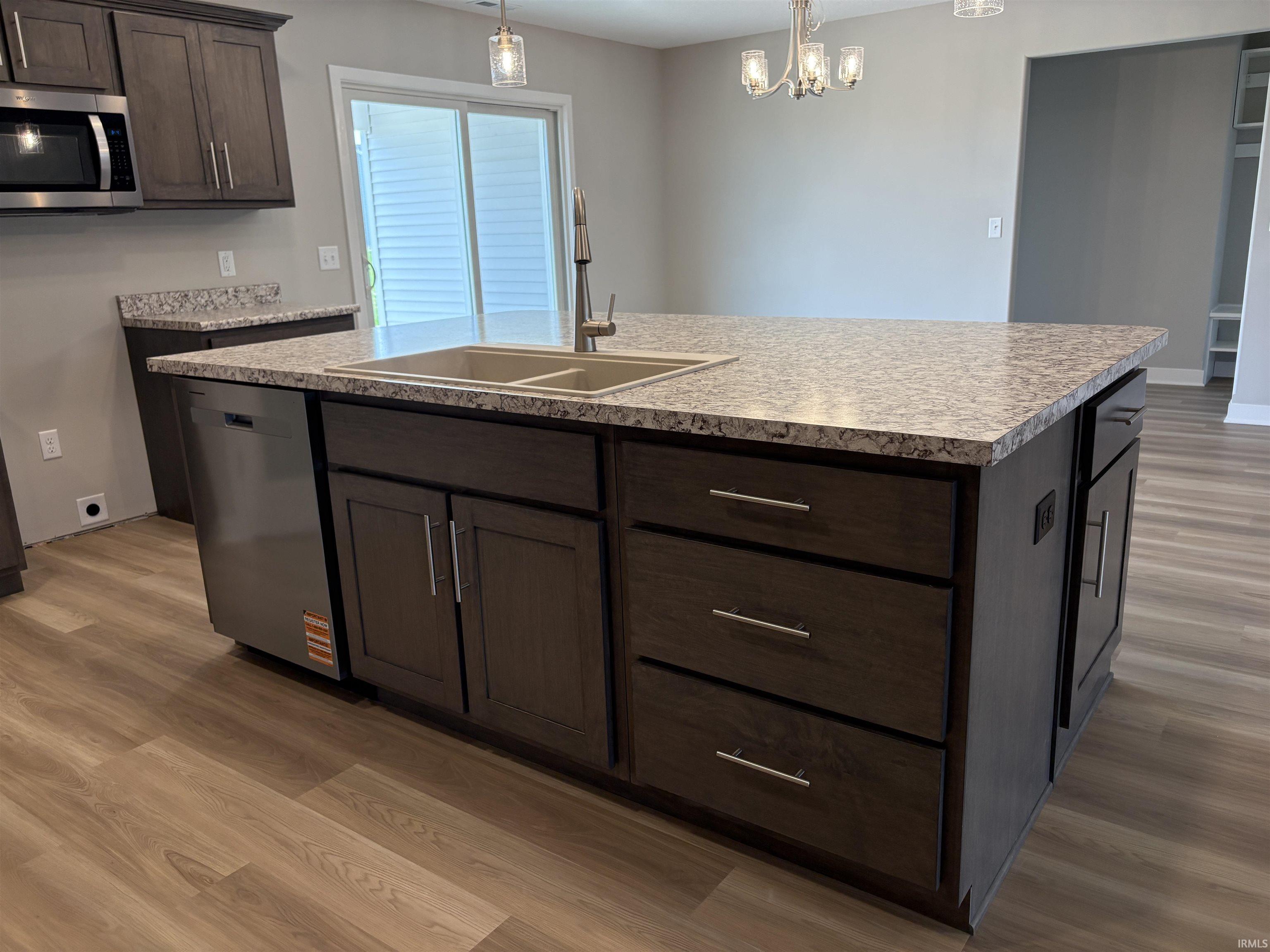 Kitchen featuring an expansive island with a double basin sink, stainless steel faucet, and ample cabinetry