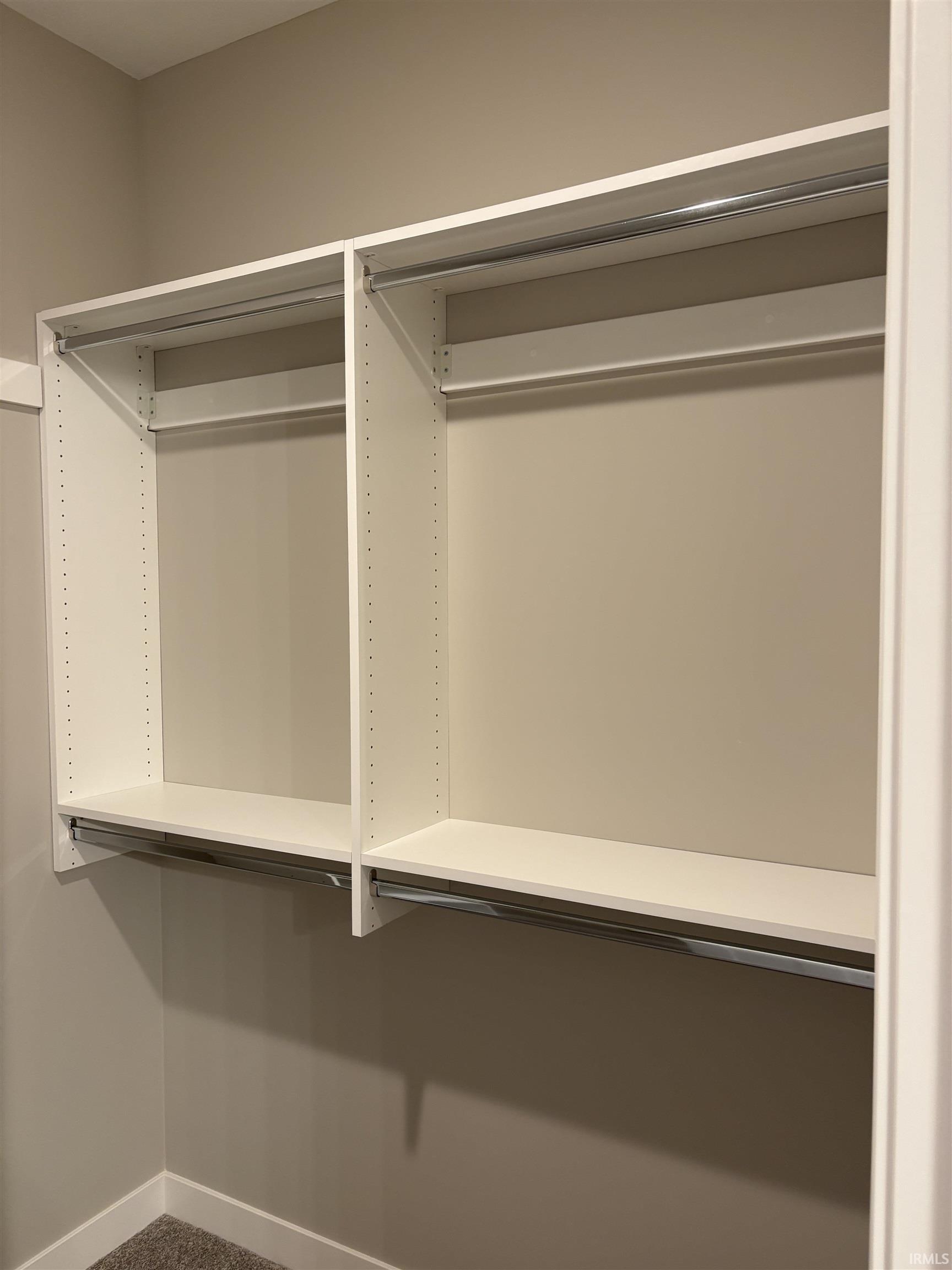 Custom white shelving system featuring adjustable shelves and multiple chrome hanging rods