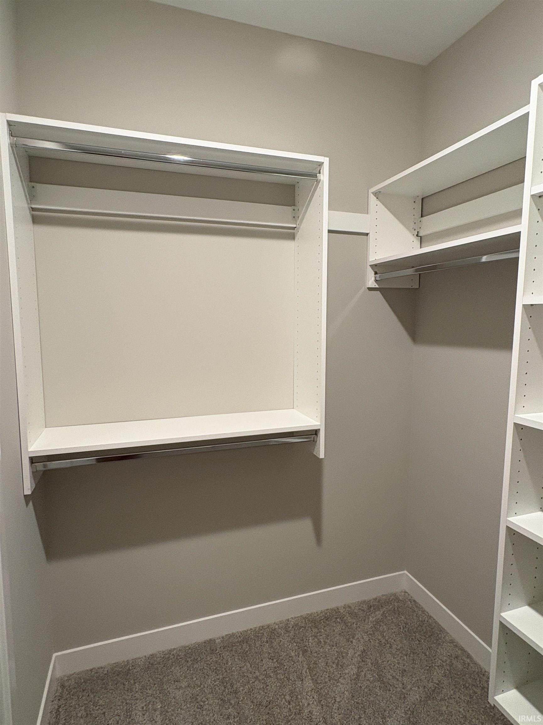Custom closet system featuring white shelving, hanging rods, and built-in compartments