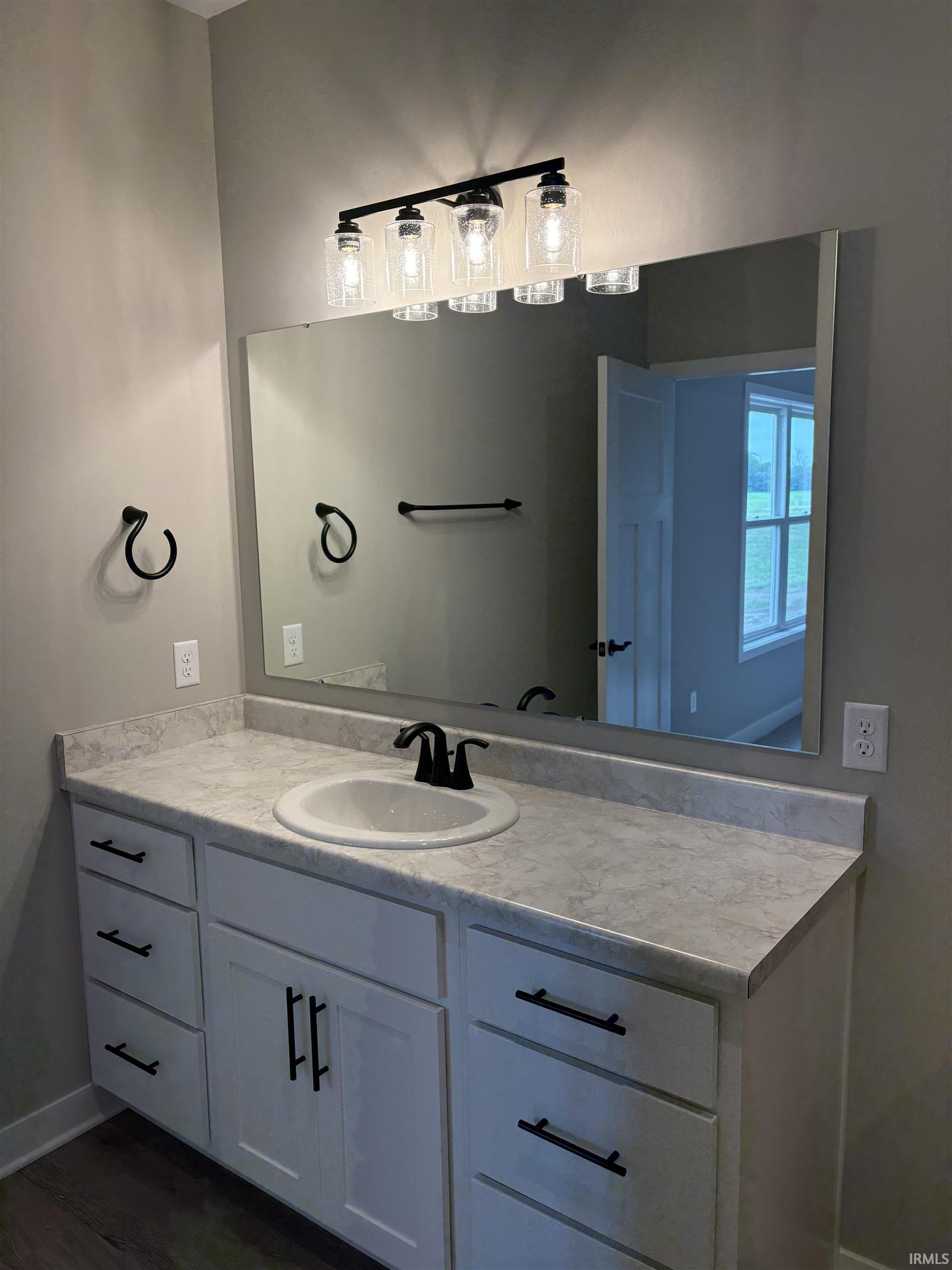 White vanity with multiple drawers and cabinet storage, featuring a single basin sink and matte black faucet