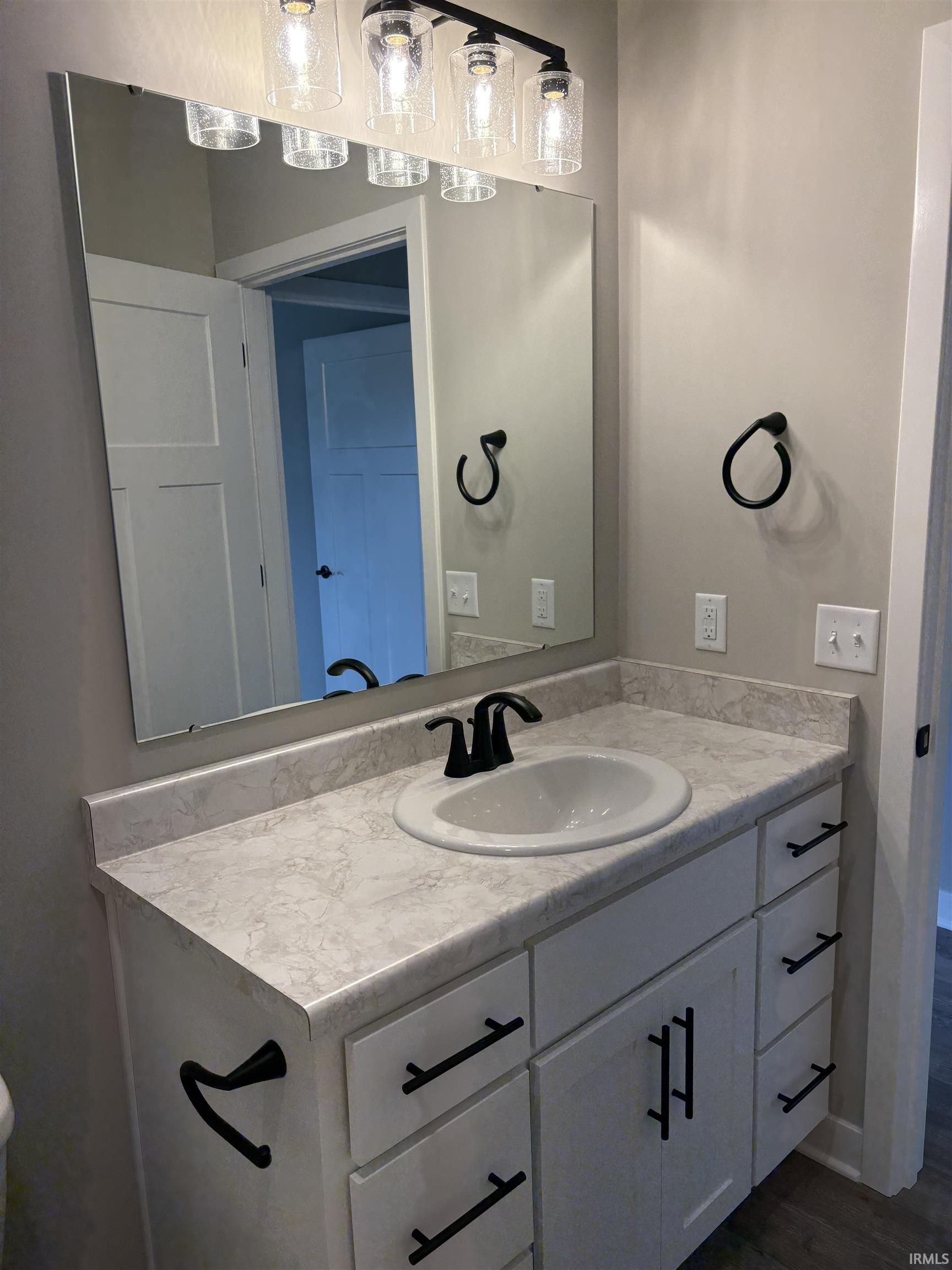 Bathroom vanity with a white integrated sink, matte black faucet, and white cabinetry