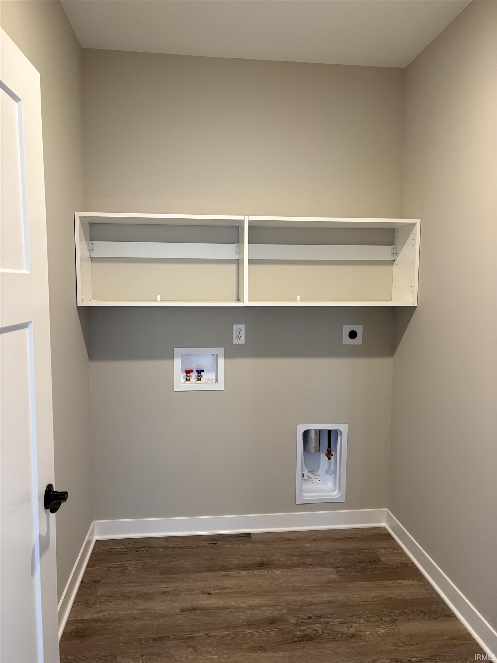 Laundry area featuring wood-finish flooring, light neutral wall color, and white trim