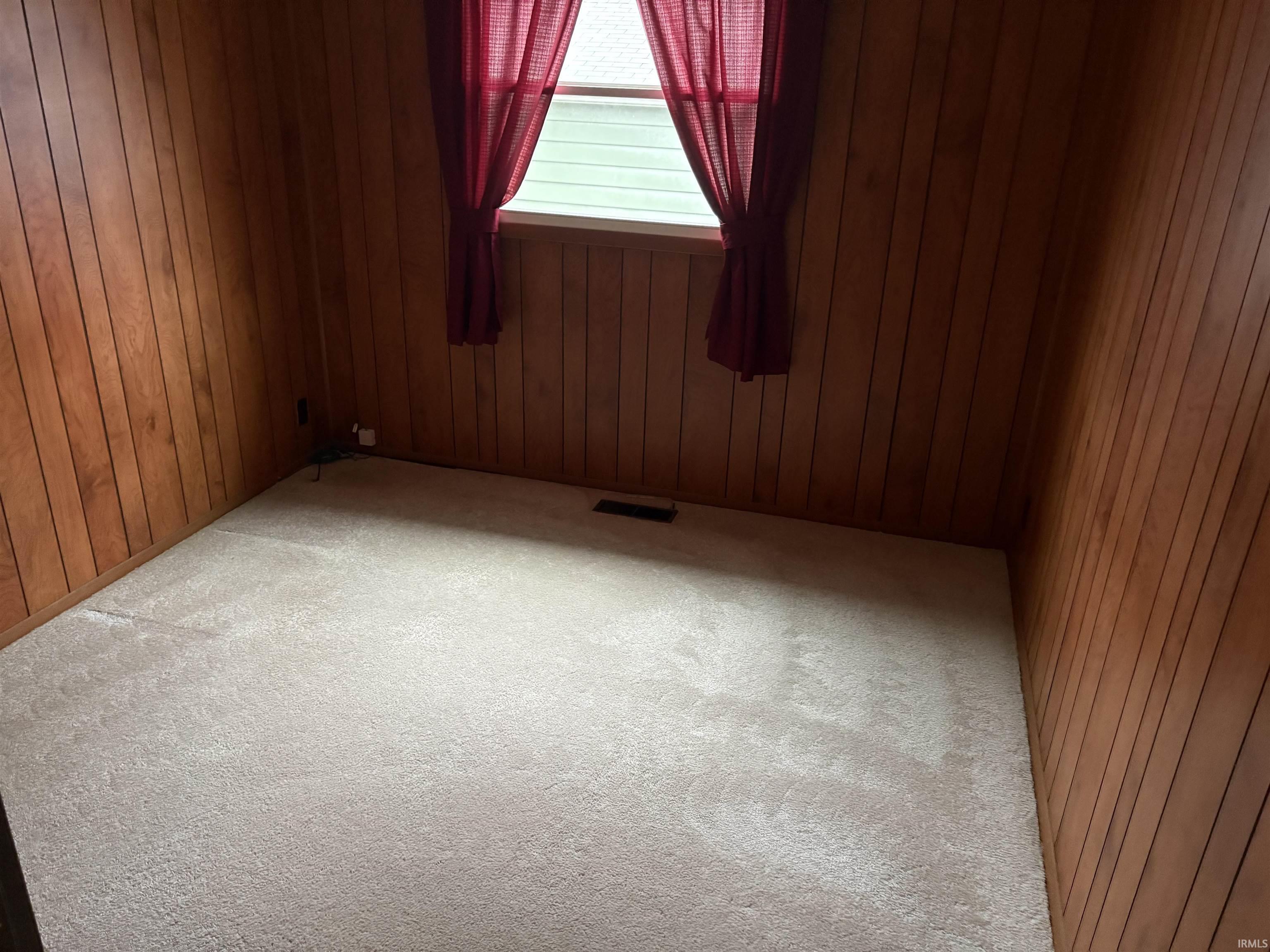 Spare room with carpet floors and wood walls