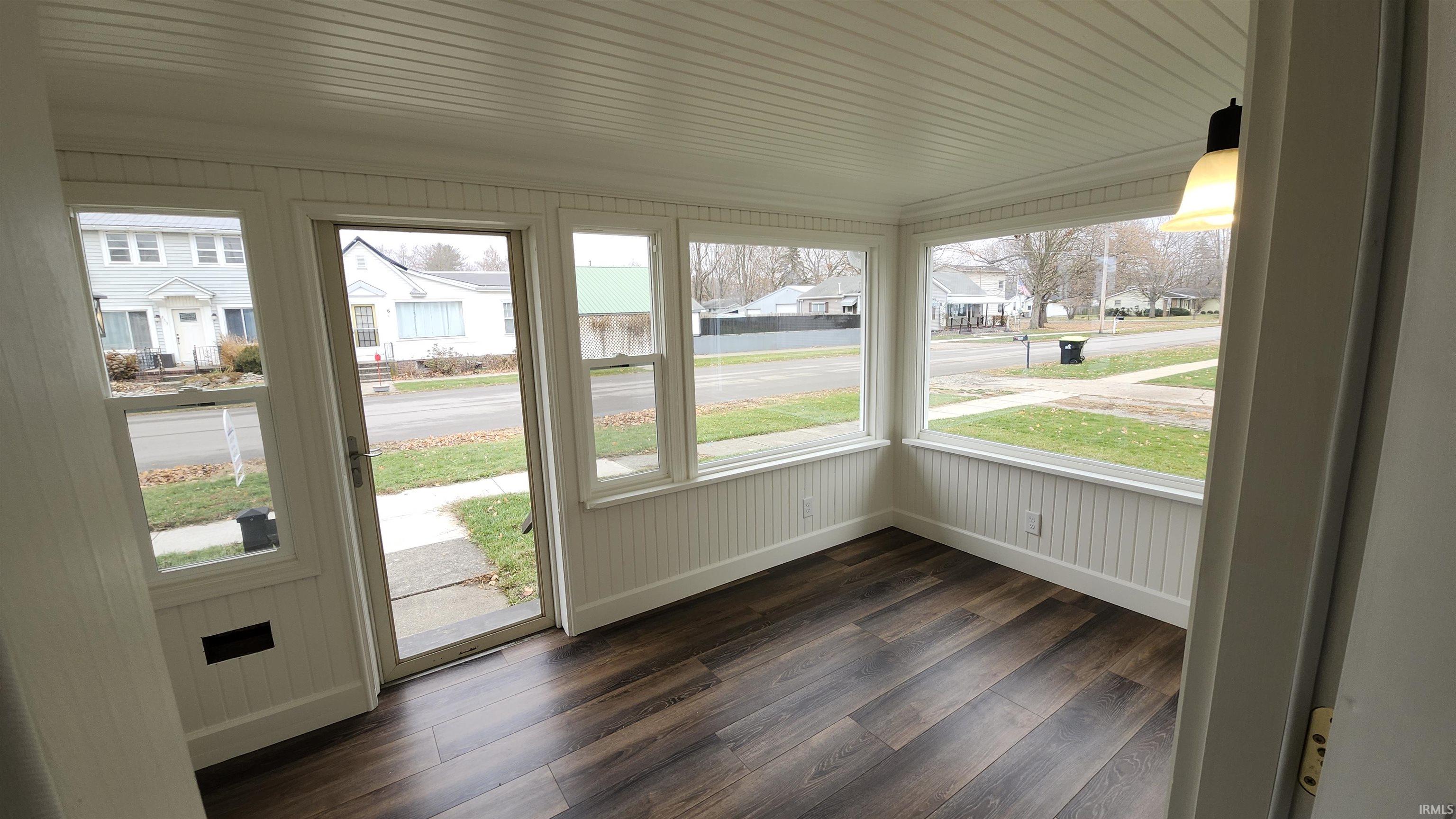 Unfurnished sunroom featuring a residential view, wood finished floors, and wooden walls