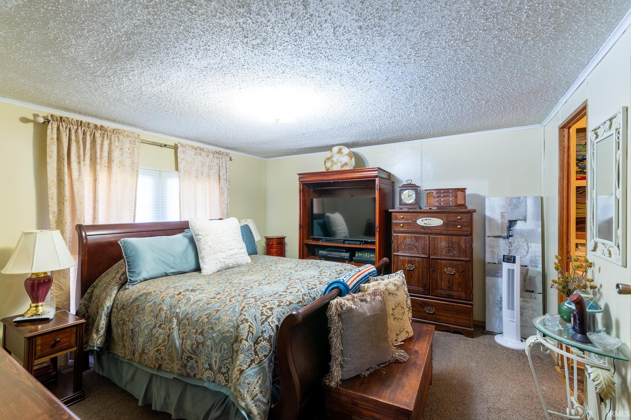 Carpeted bedroom with a textured ceiling and crown molding