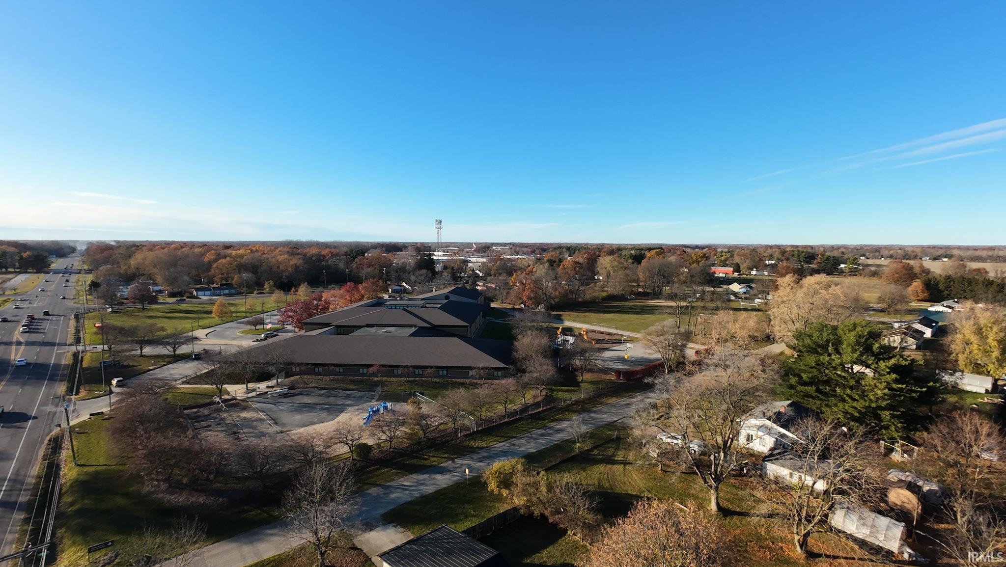 Aerial view of property and surrounding area with a tree filled landscape