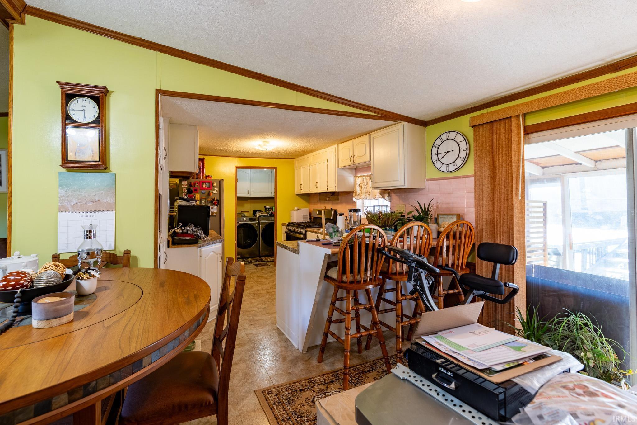 Dining area featuring ornamental molding, independent washer and dryer, and vaulted ceiling