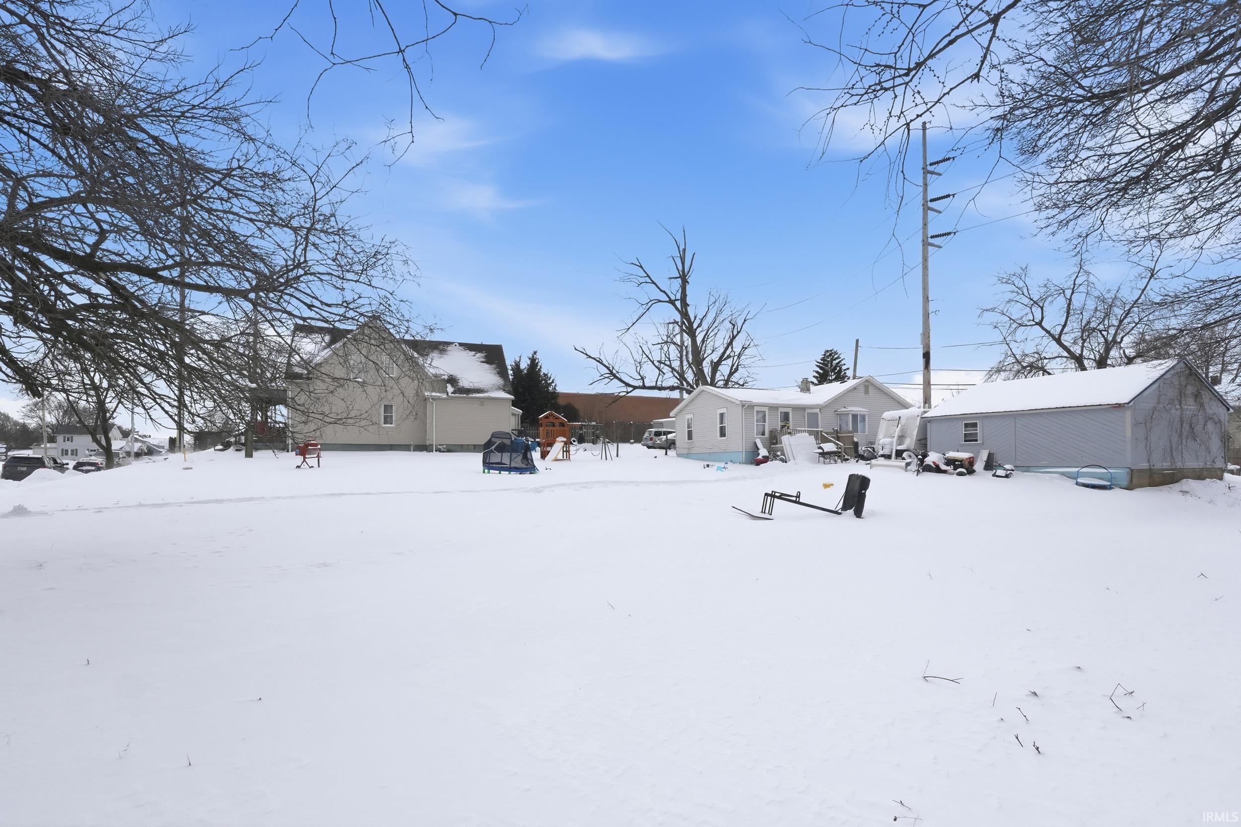 Snow covered back of property featuring an outbuilding and a residential view