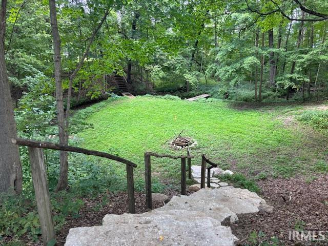 View of green lawn featuring stairway and a forest view
