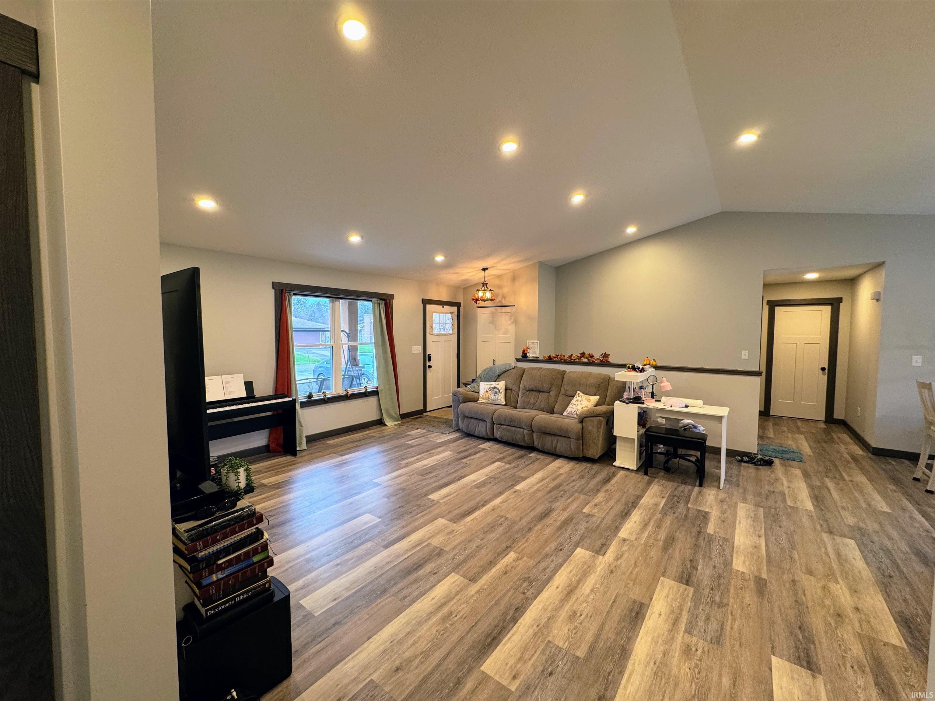 Living area featuring vaulted ceiling, wood finished floors, and recessed lighting