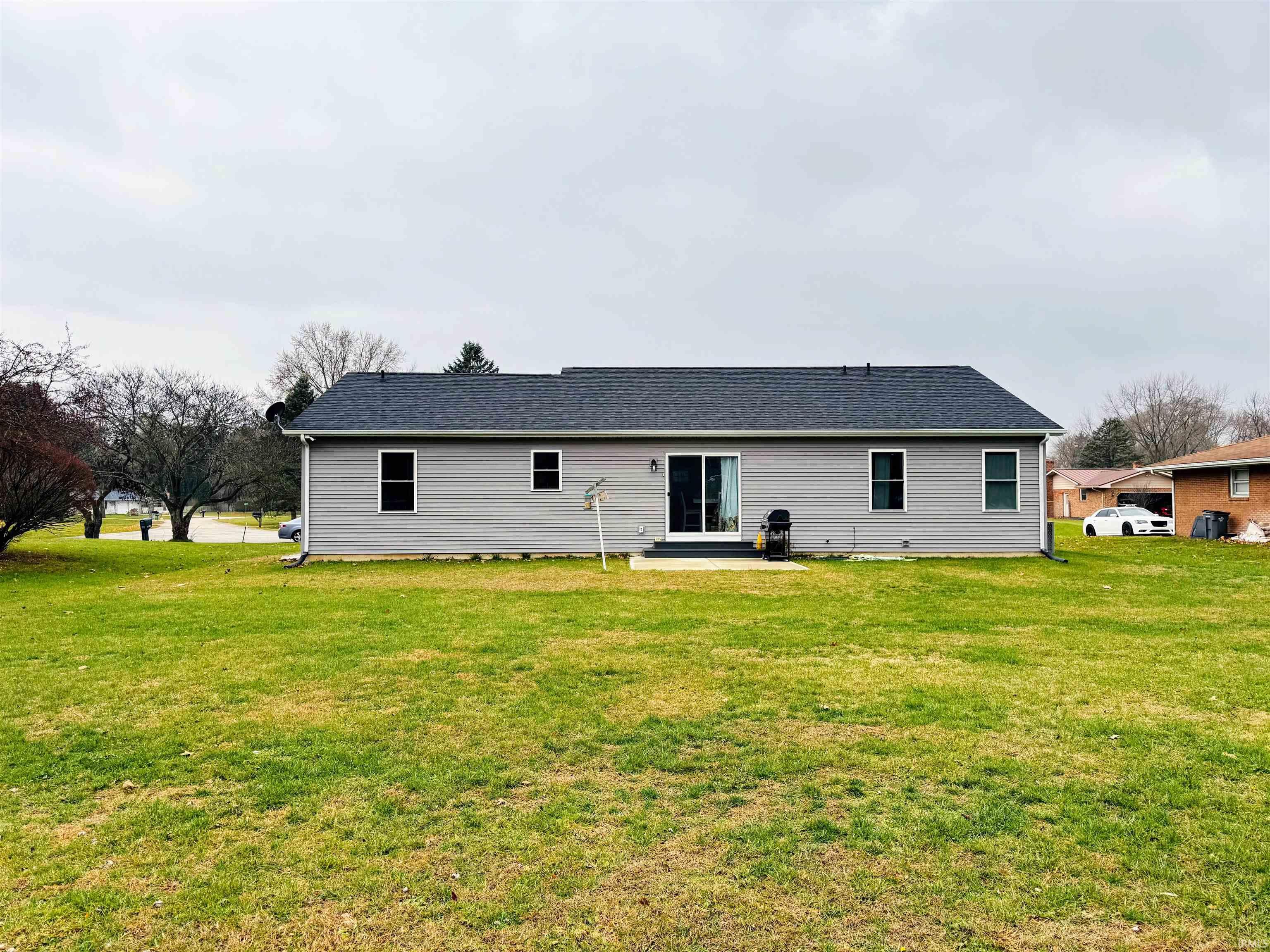 Back of property with a patio area, a lawn, and roof with shingles