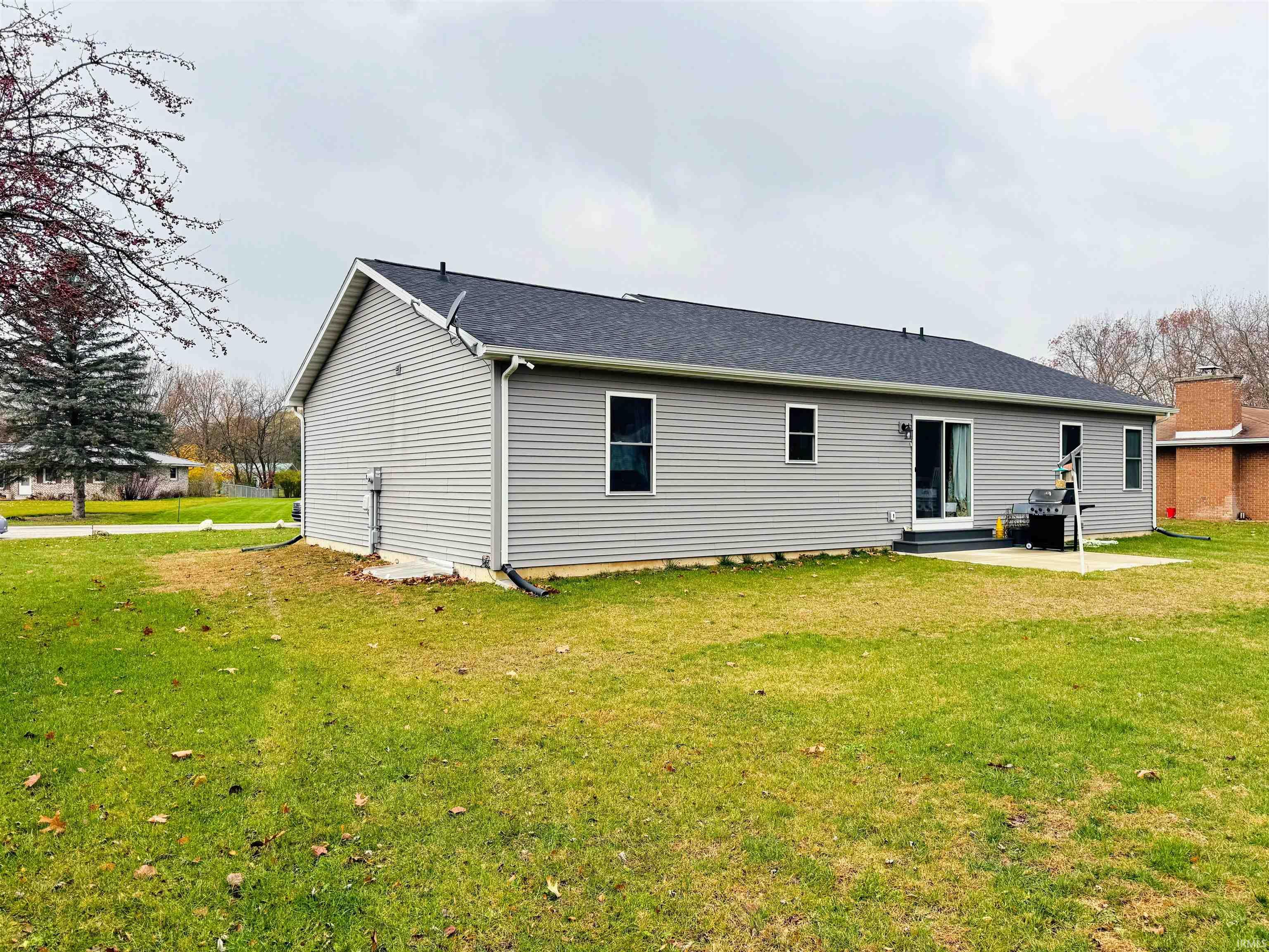 Back of house featuring a lawn, a patio, a shingled roof, and entry steps