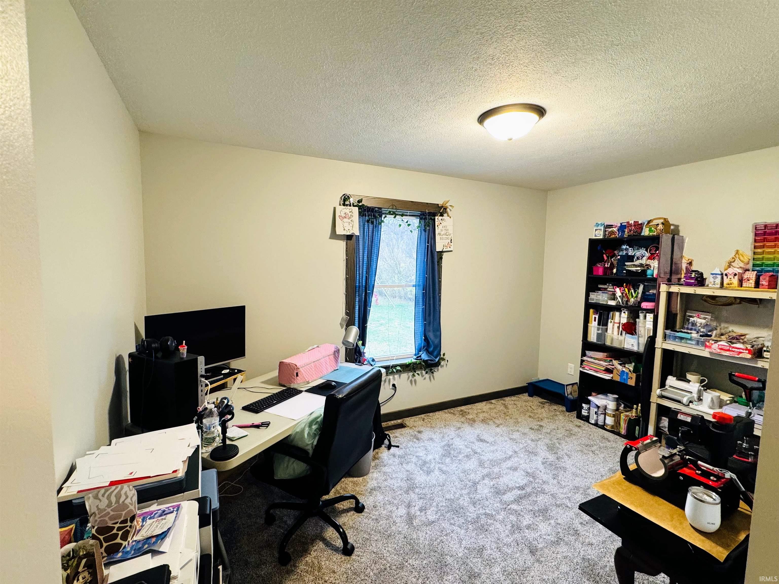 Office featuring a textured ceiling and light colored carpet