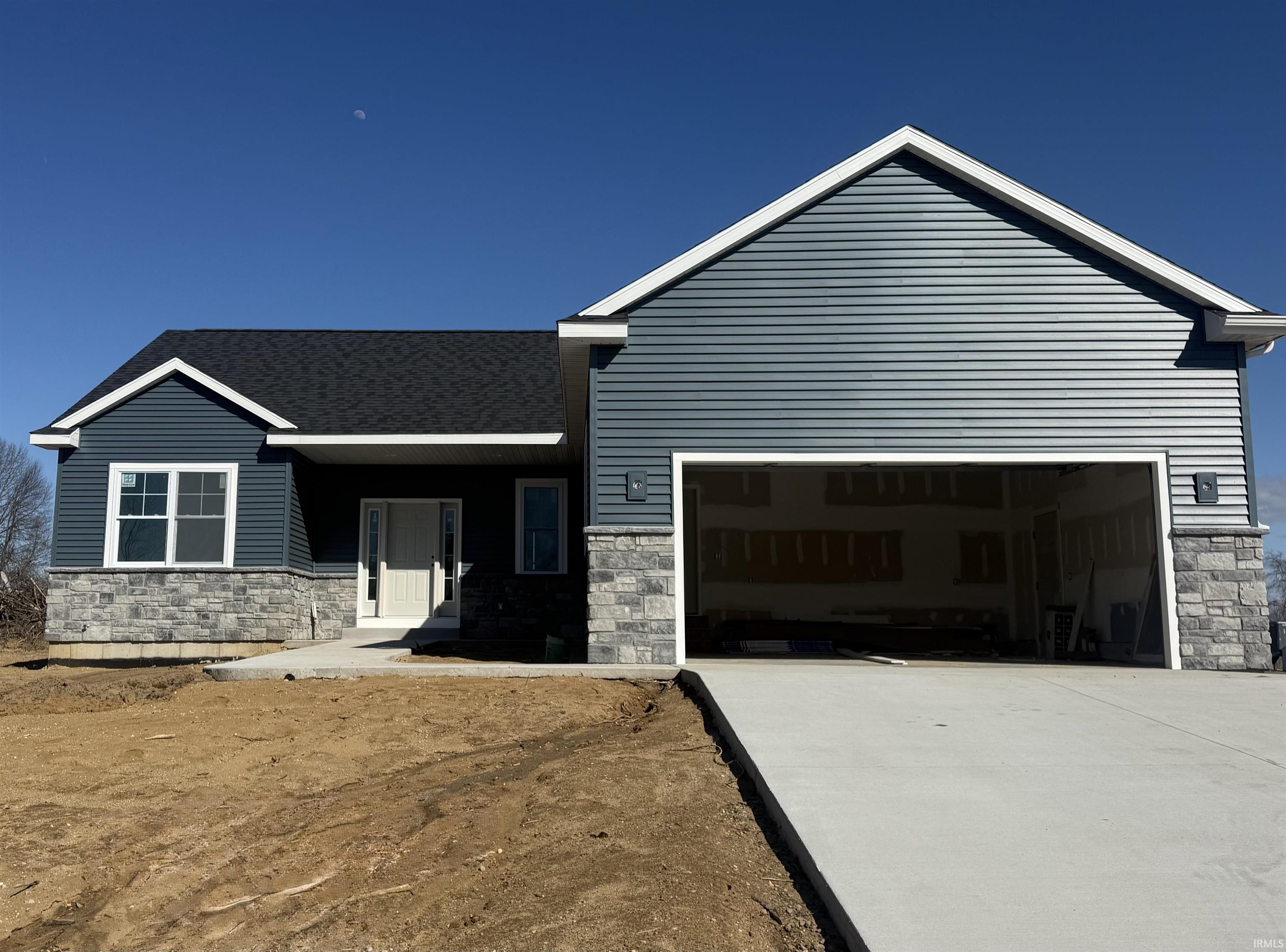 View of front of house featuring stone siding, a garage, driveway, and covered porch