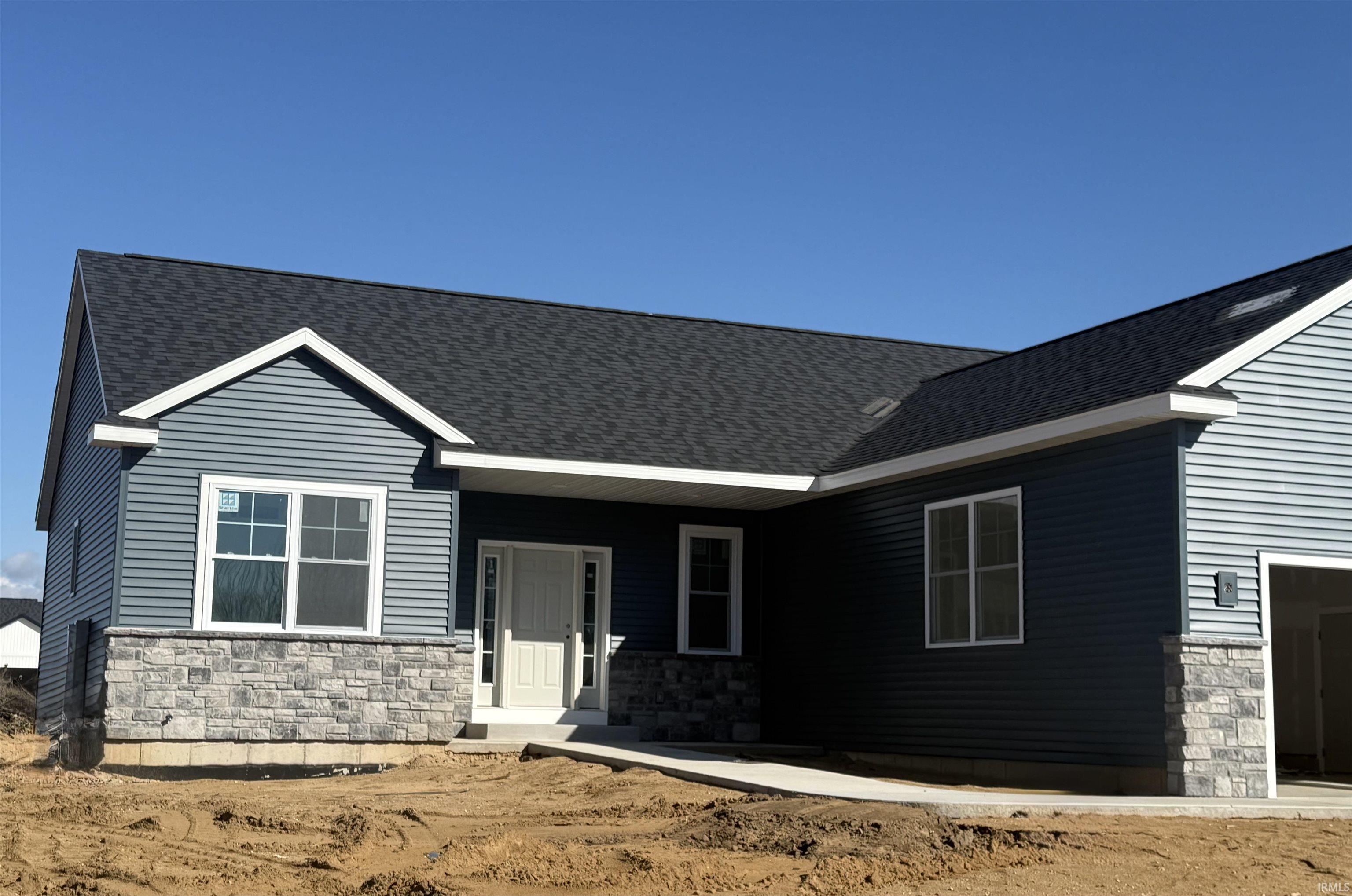 View of front of home featuring stone siding, a porch, and roof with shingles