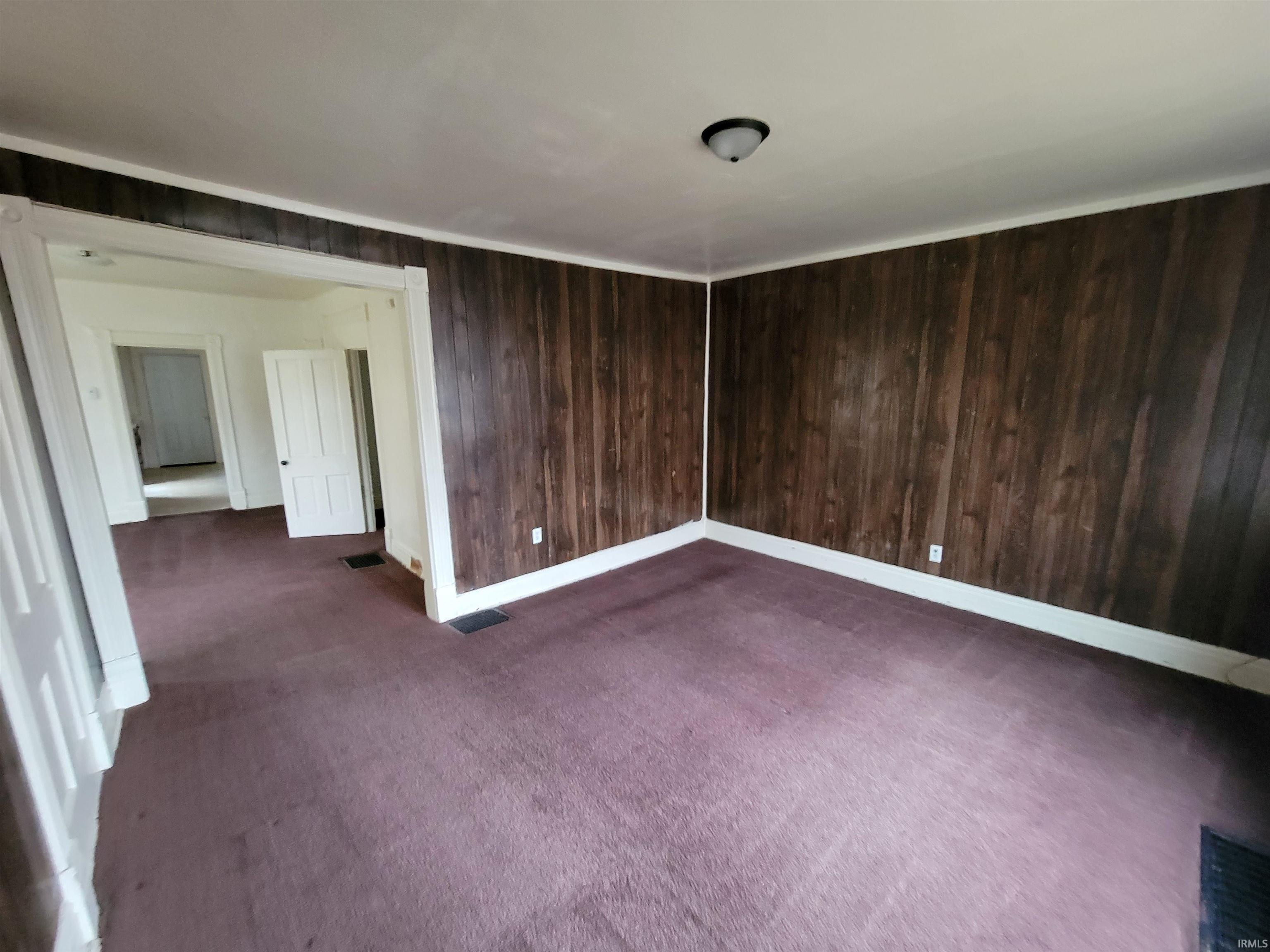 Spare room with wooden walls and dark carpet