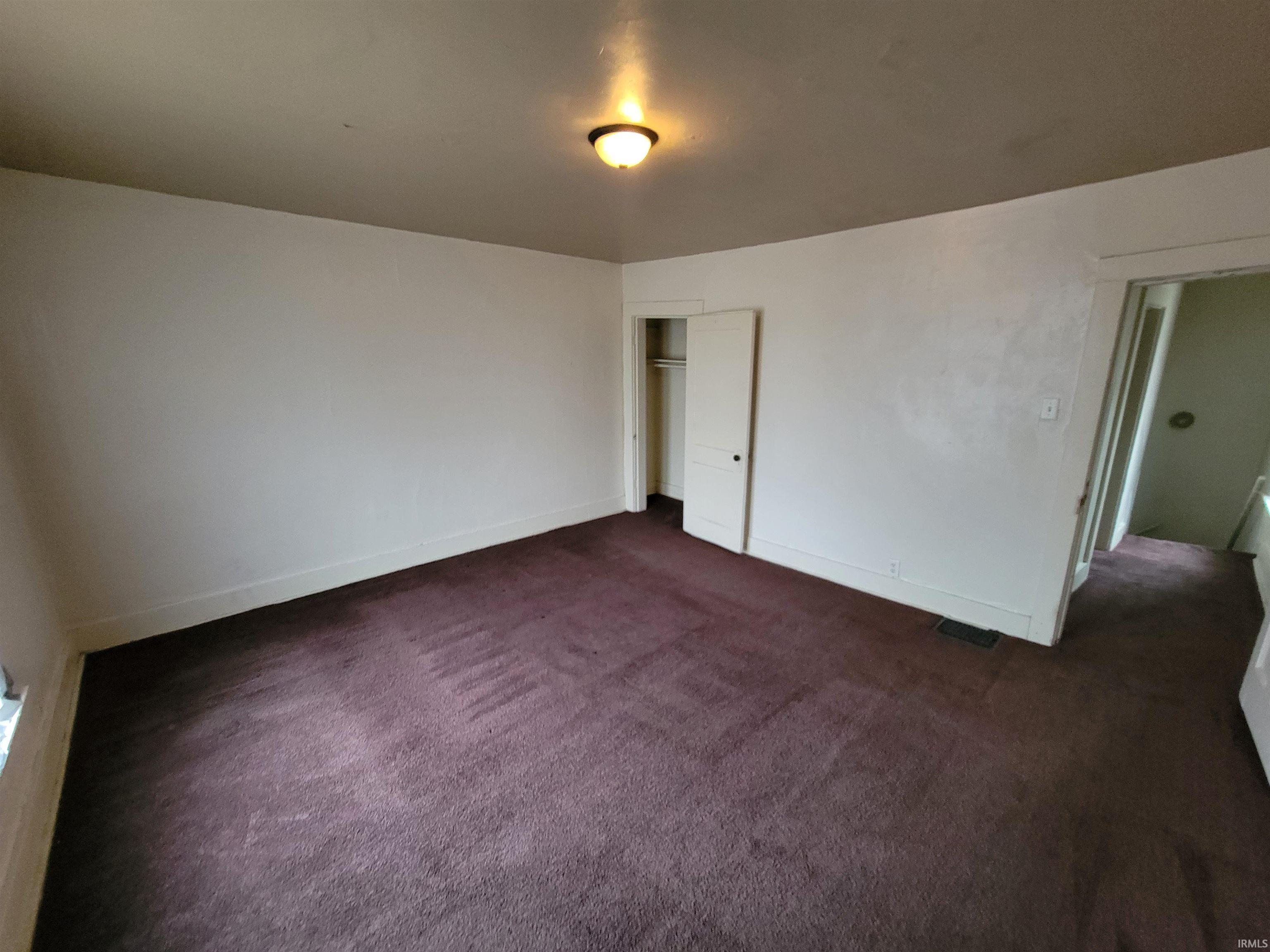 Unfurnished bedroom featuring dark carpet and a closet