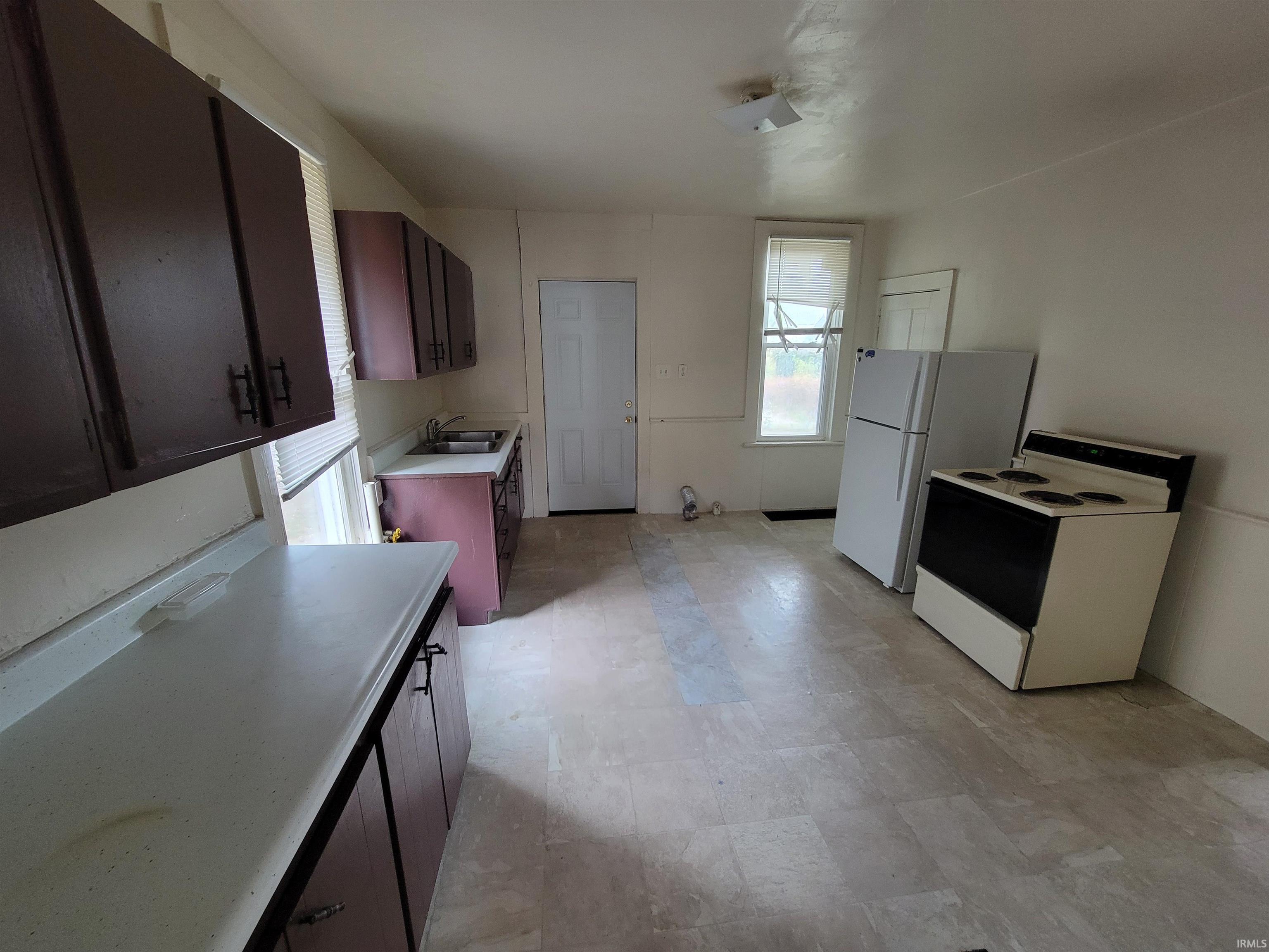 Kitchen with white appliances, light countertops, and dark brown cabinets