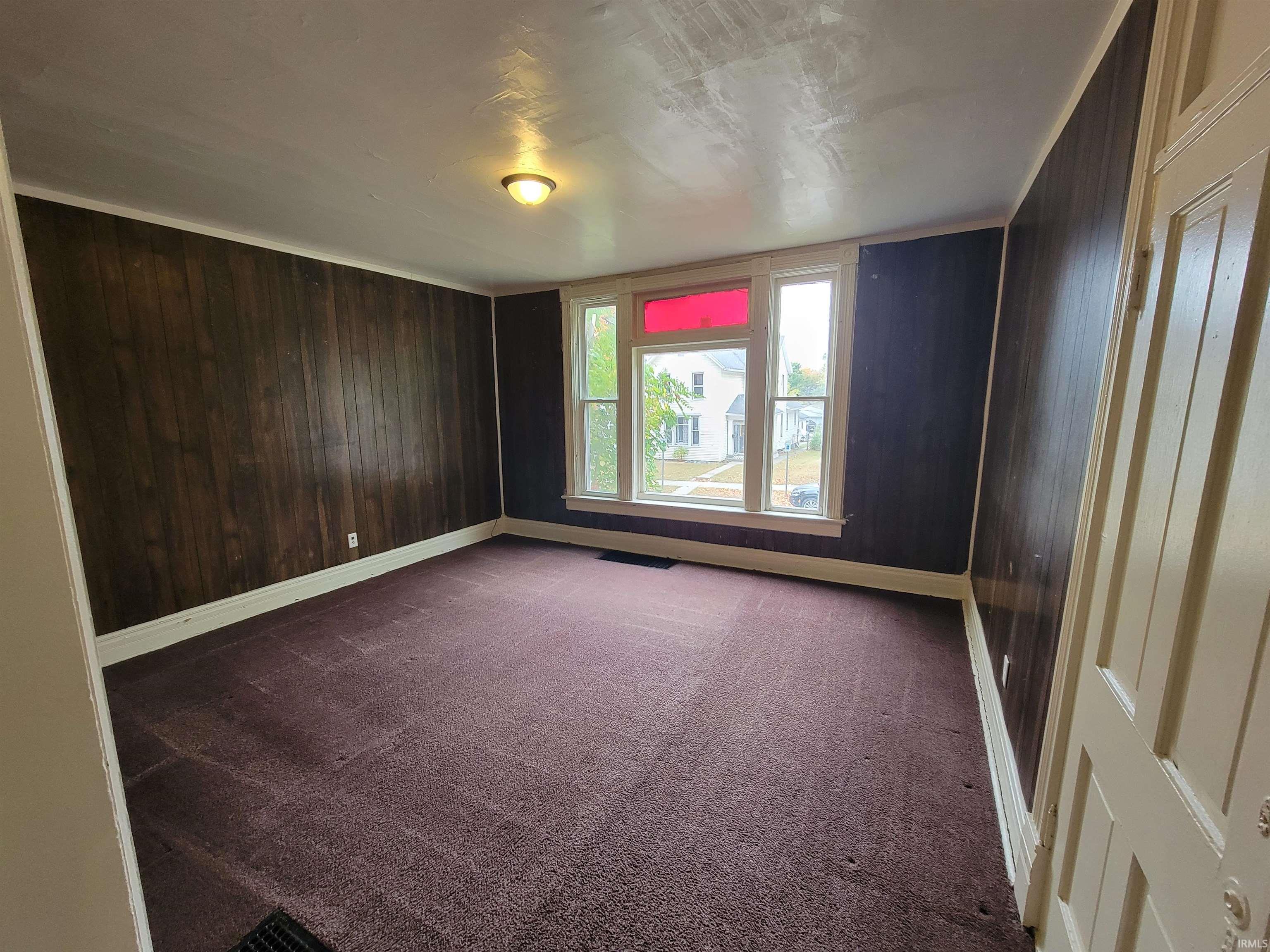 Unfurnished room with dark carpet and wooden walls