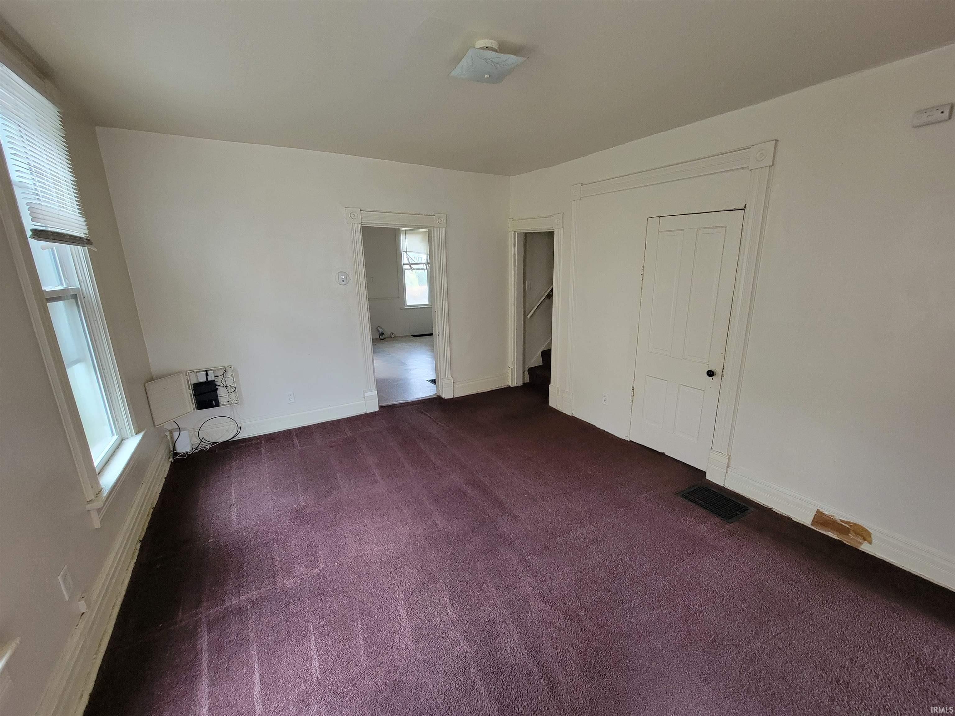 Unfurnished bedroom featuring dark carpet, a closet, and heating unit