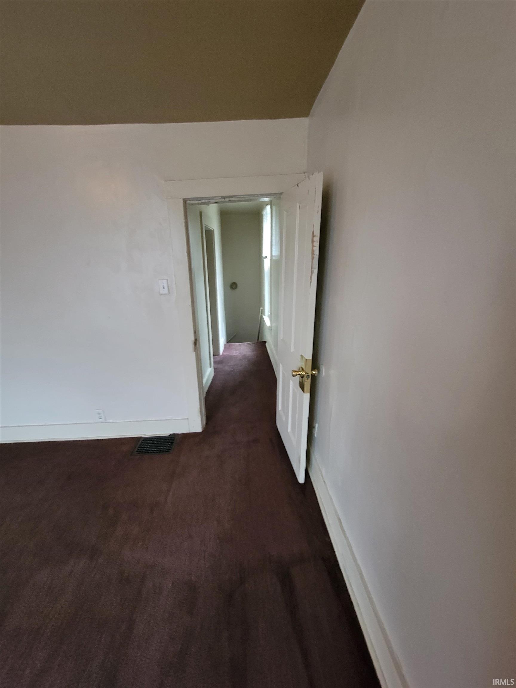 Empty room featuring baseboards and dark colored carpet