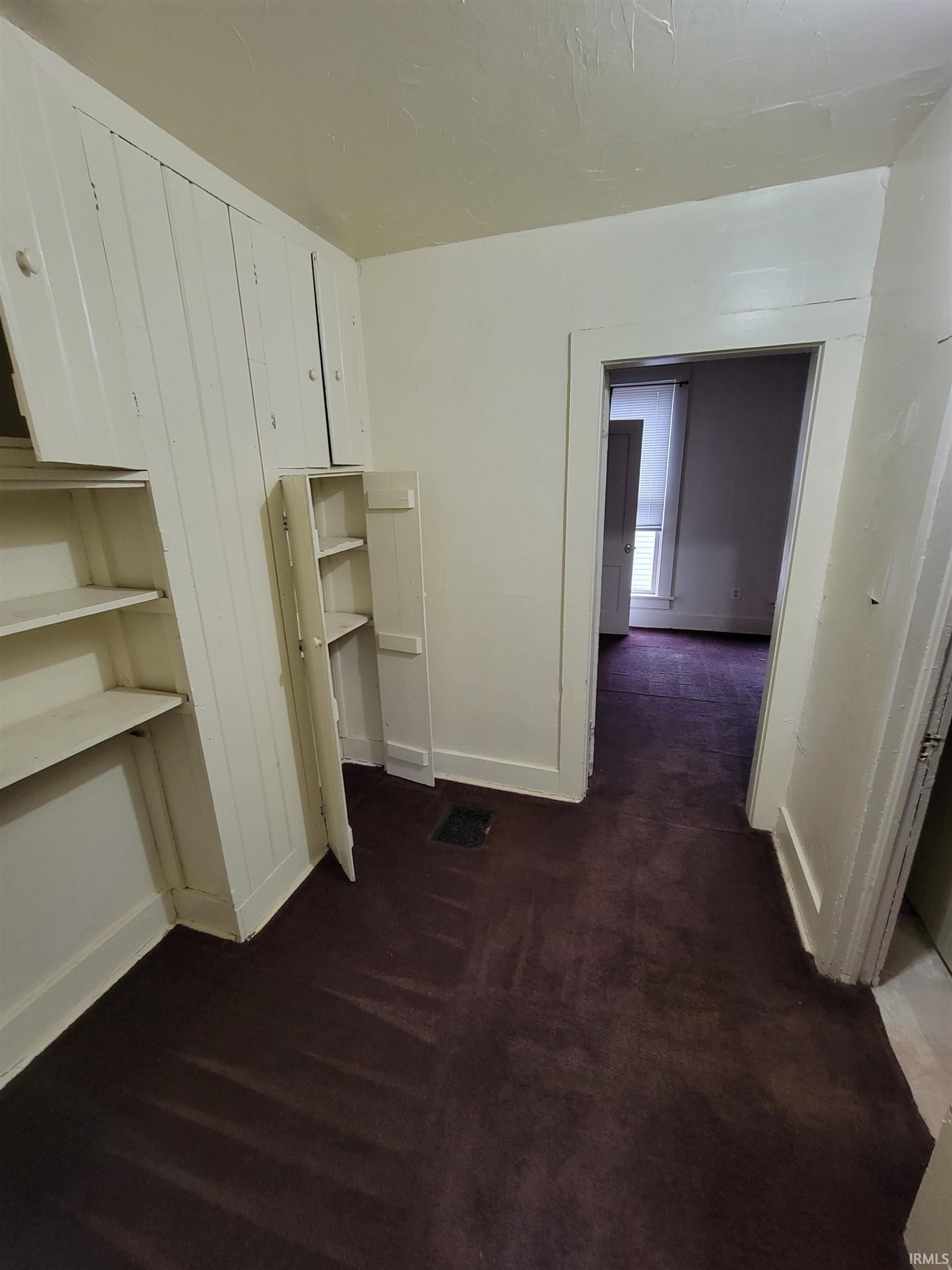Unfurnished bedroom with baseboards and dark colored carpet